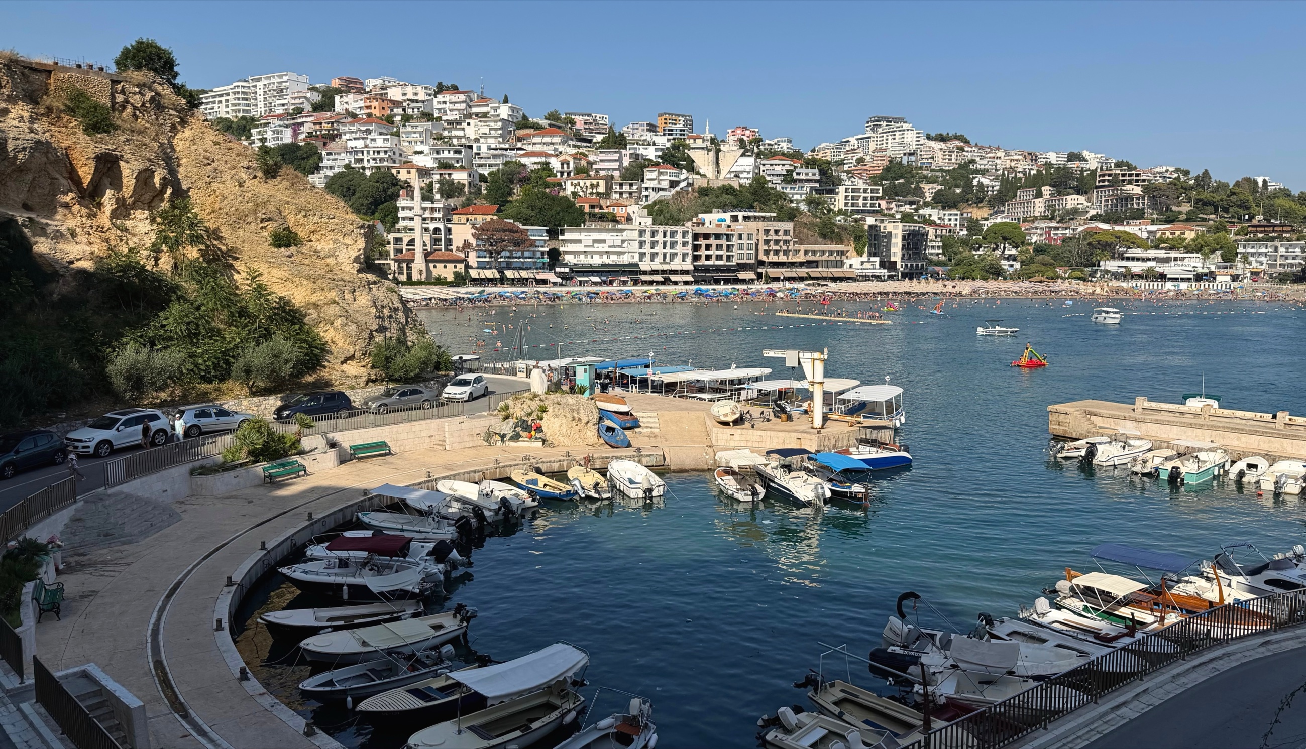 Ulcinj waterfront with the marina, Mala Plaža, hillside apartments, and Old Town.