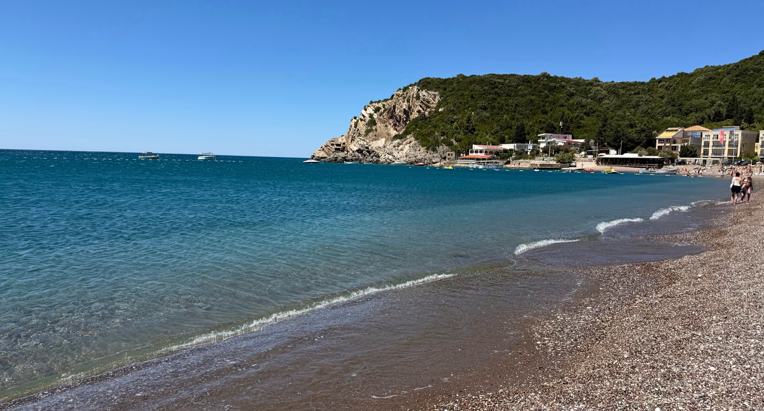 Čanj Beach with clear water and green hills behind the shore