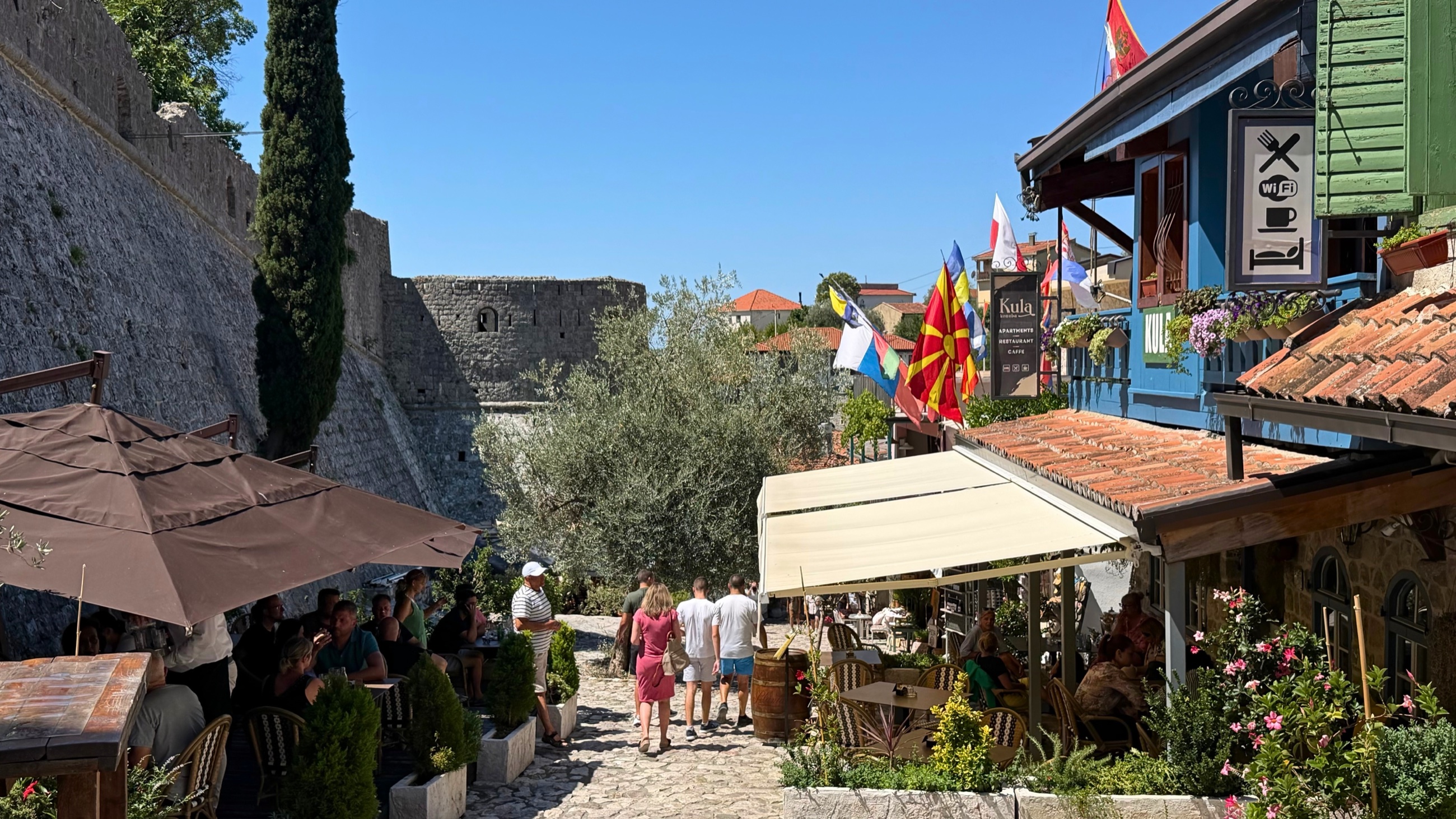 Stone lanes, cafés, and flags below the walls of Stari Bar