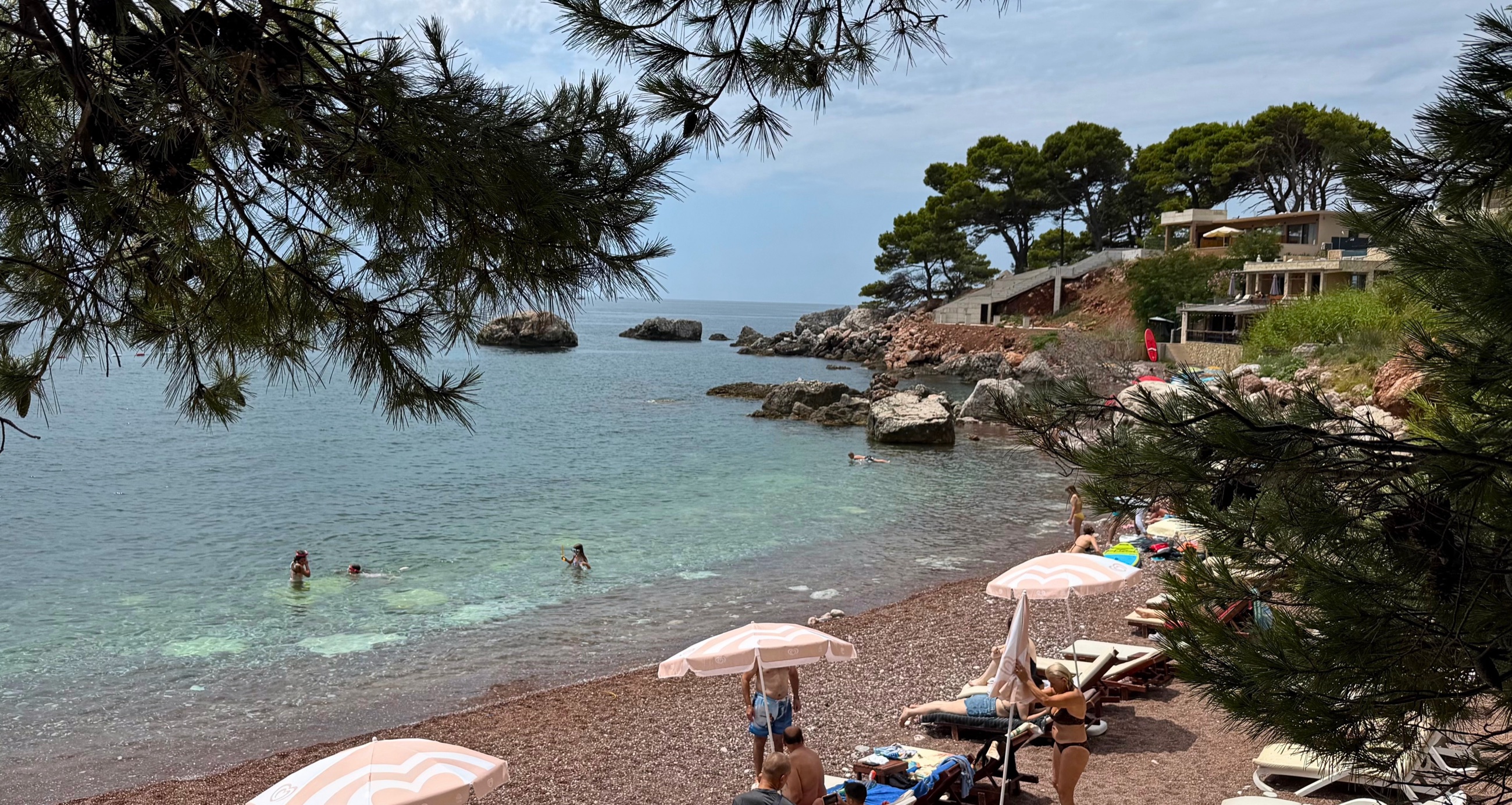 Red Beach framed by pine branches with clear blue-green water