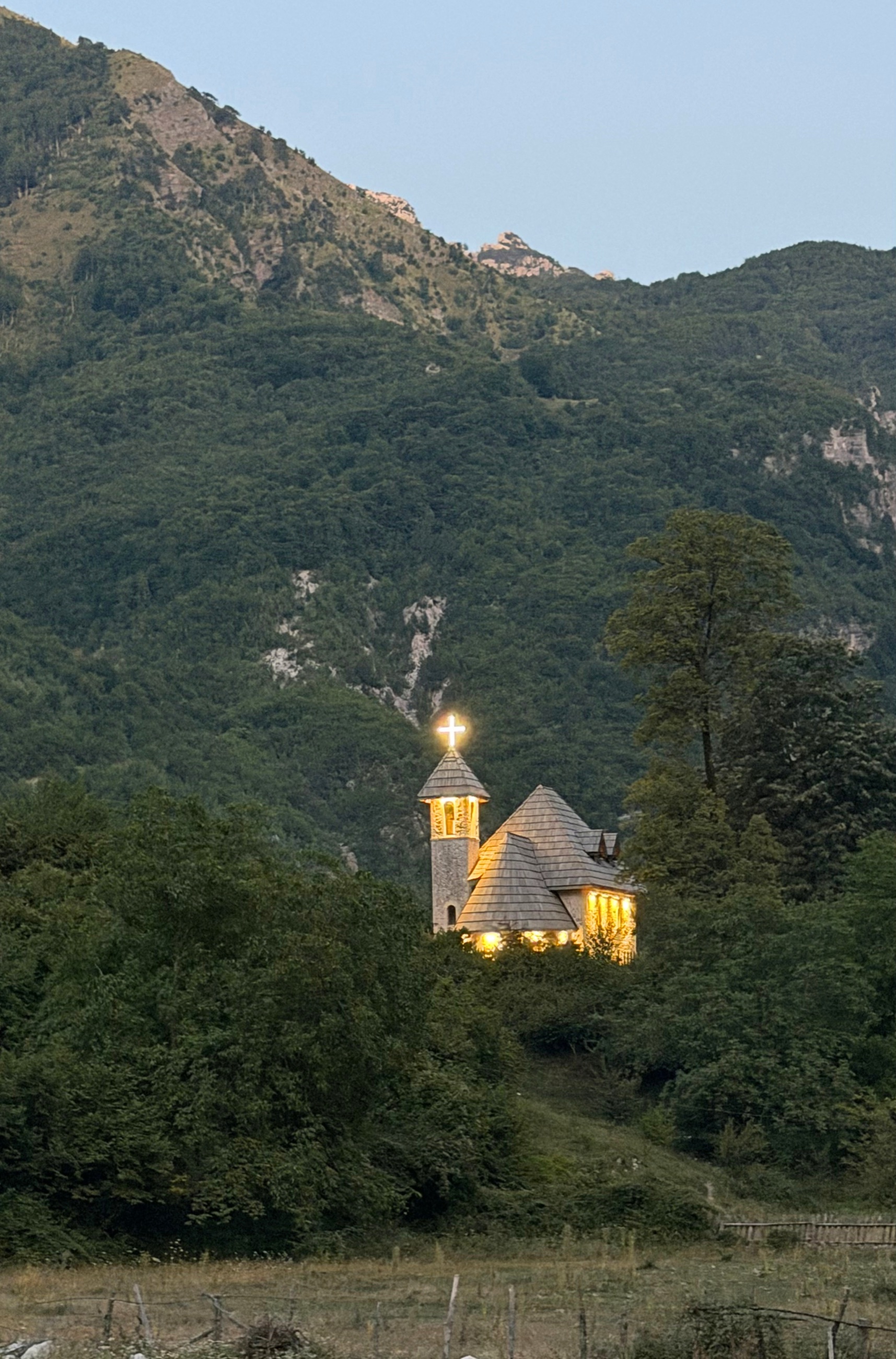The Church of Theth illuminated at dusk beneath dark mountain slopes.
