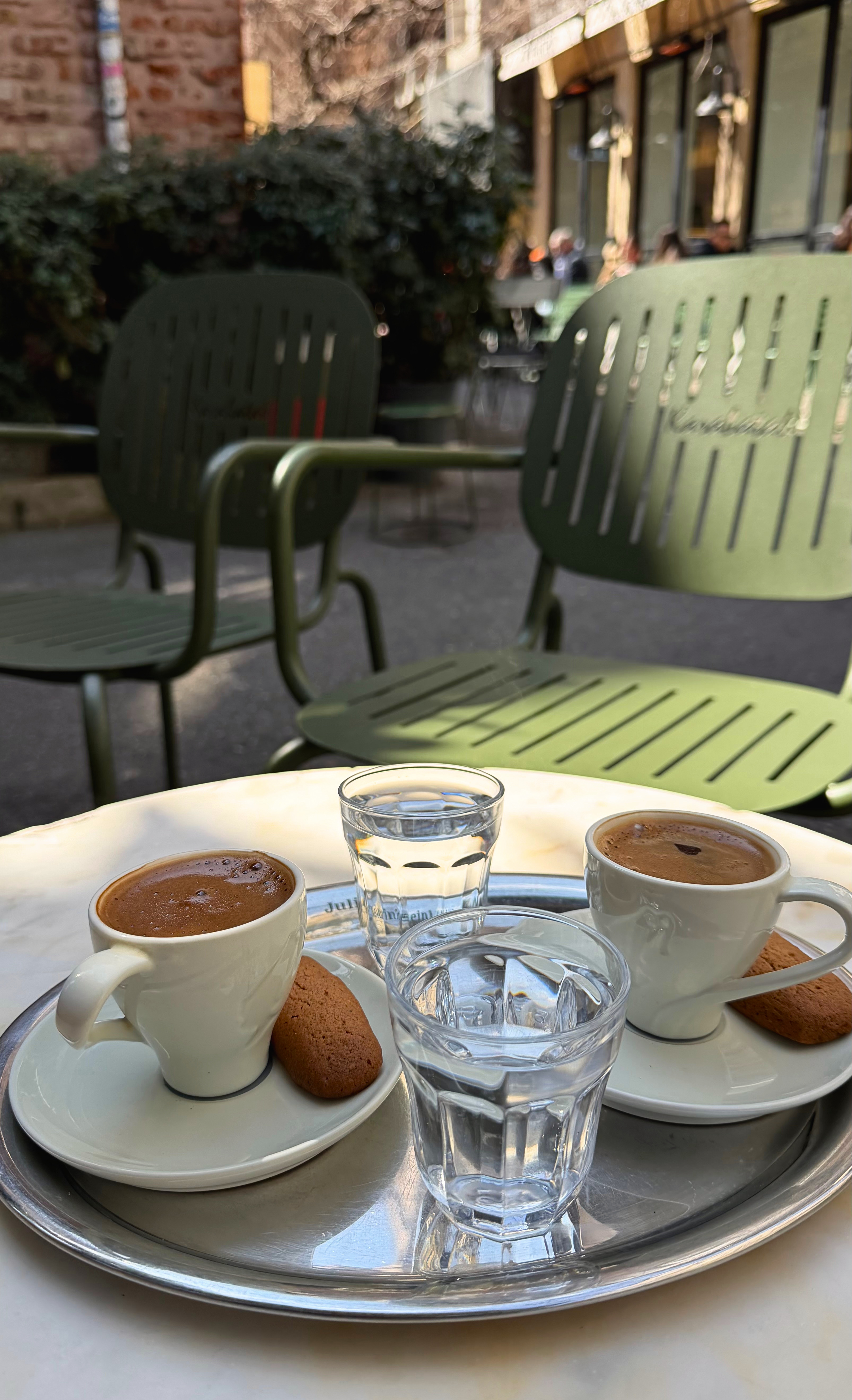 Two cups of Turkish coffee served on a metal tray outdoors.