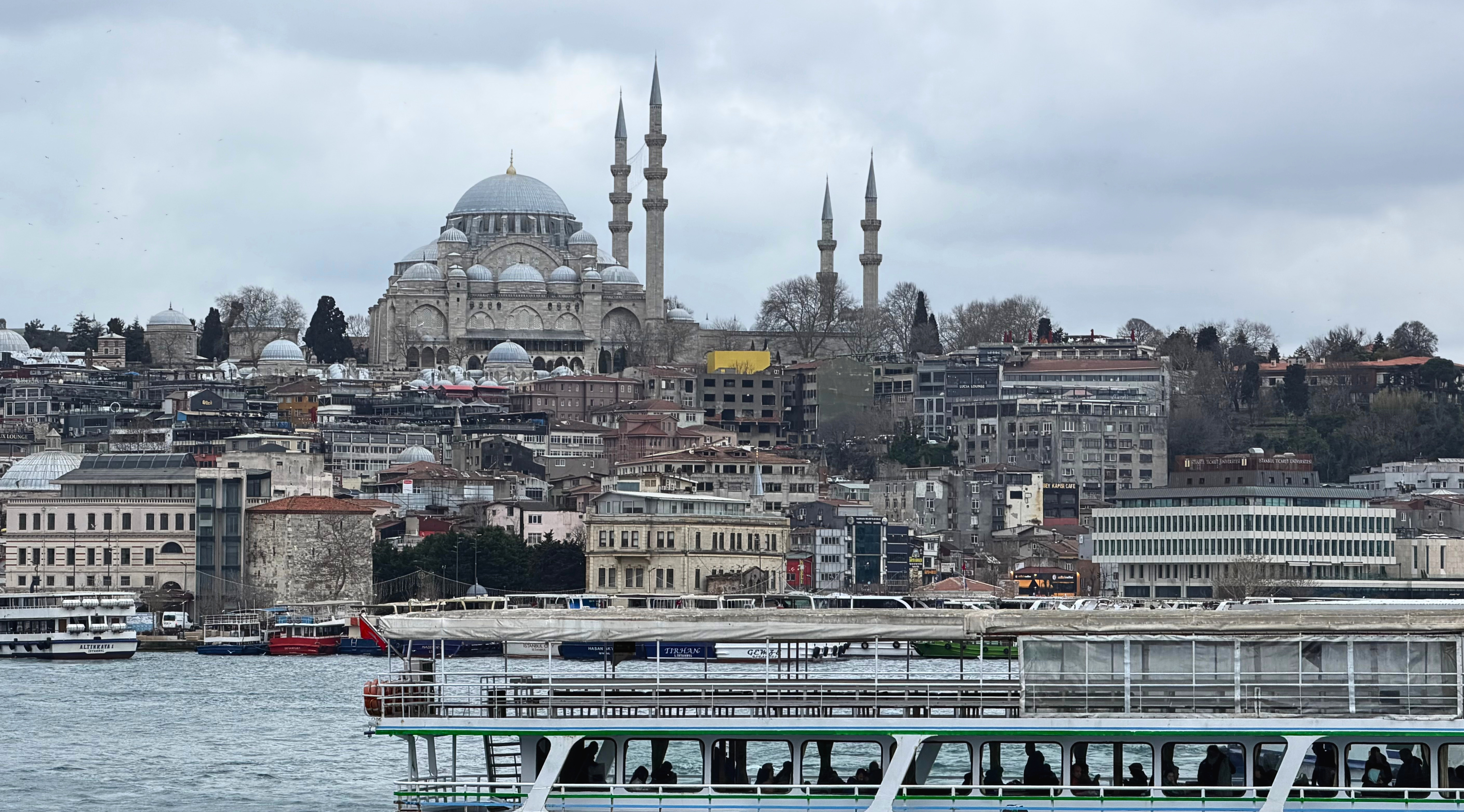 A mosque and hillside buildings seen across the water from an Istanbul ferry.