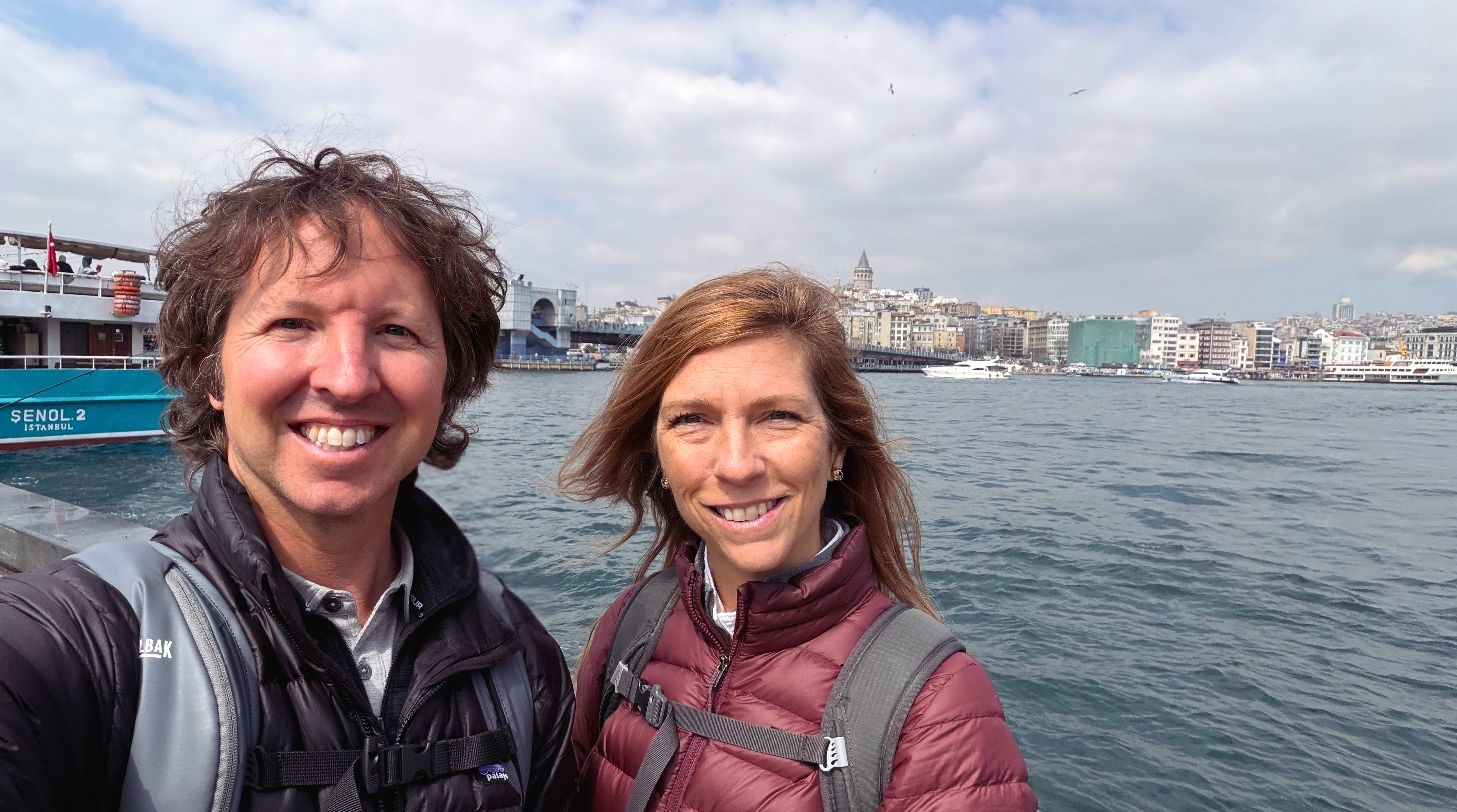 Sam and Stephanie standing by the Bosphorus with Galata Tower and the Istanbul waterfront behind them.