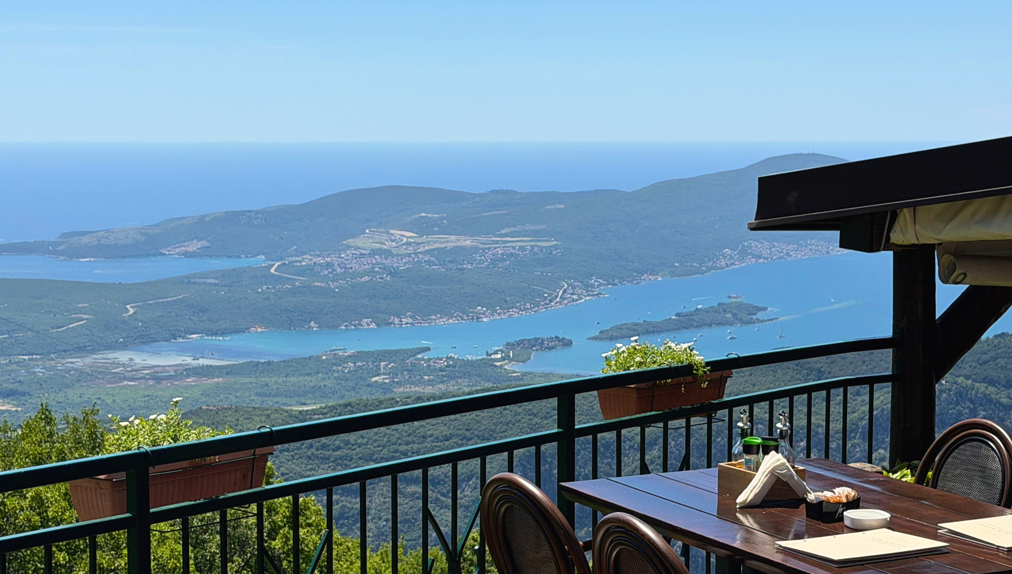 A table at Nevjesta Jadrana set high above the Bay of Kotor, the Adriatic visible beyond the mountains.