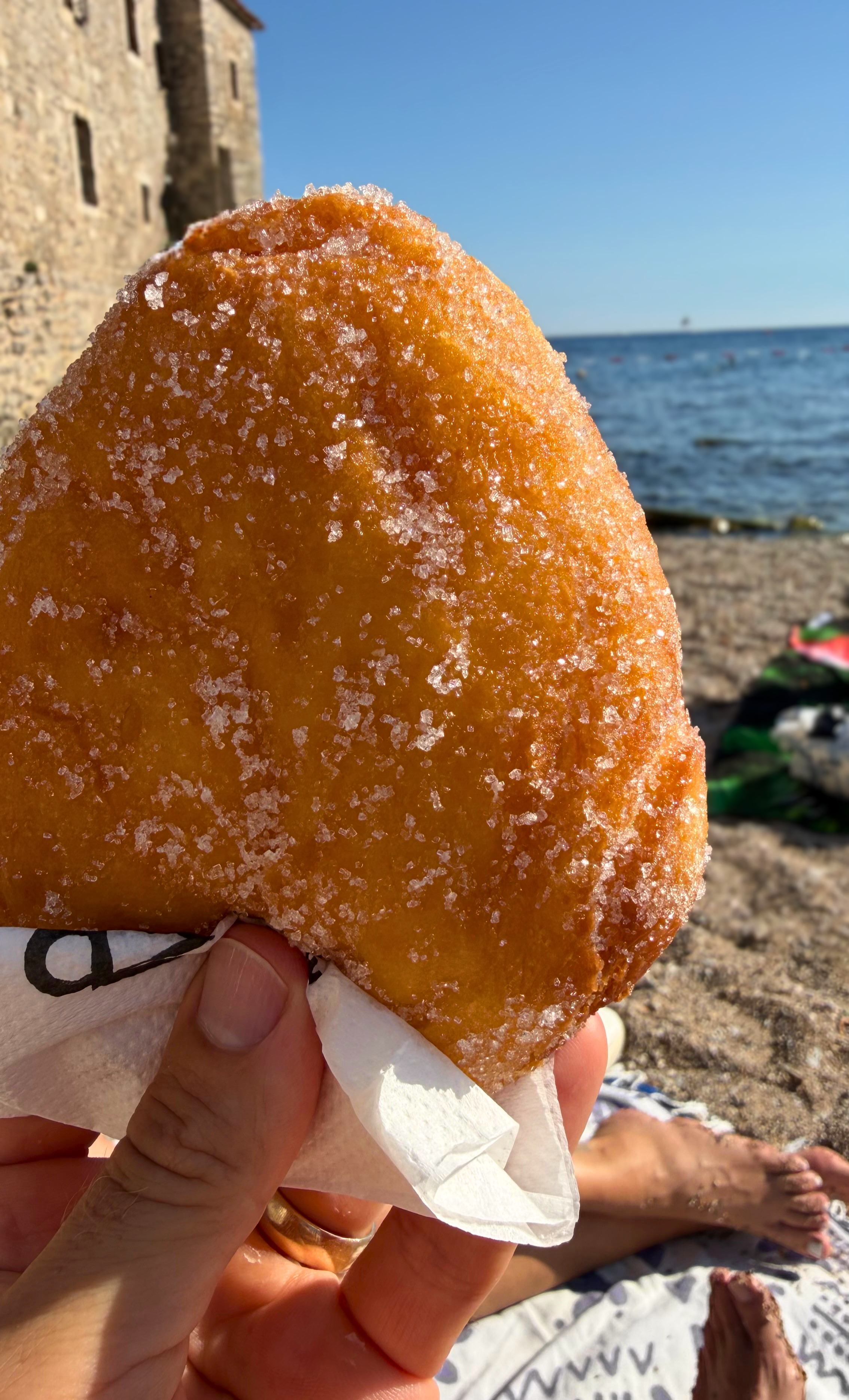 Mekike, the large Balkan fried dough dusted with sugar, on the beach just outside Budva's Old Town walls