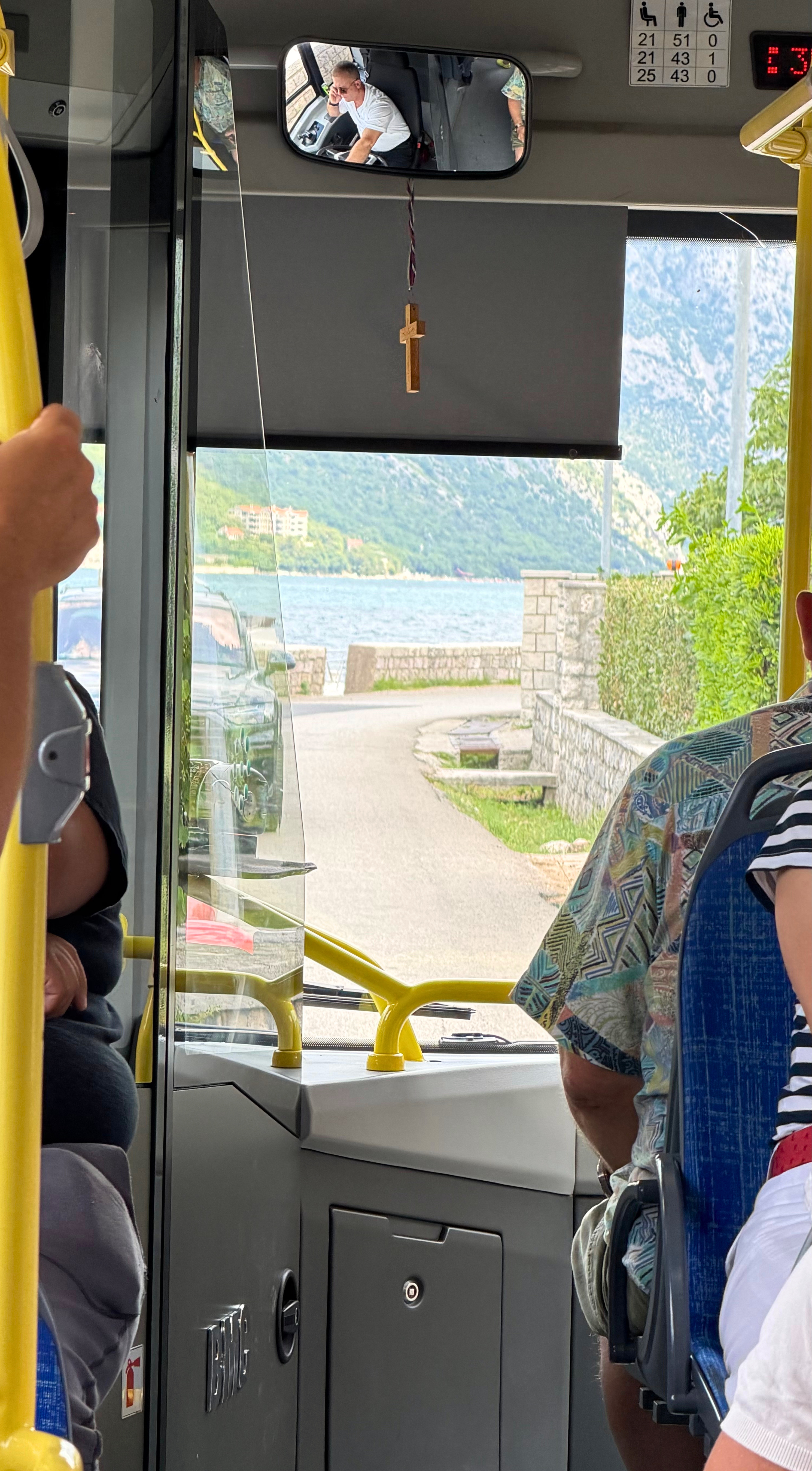 The Blue Line bus following the shoreline road from Tivat back toward Kotor, the bay appearing through the windshield