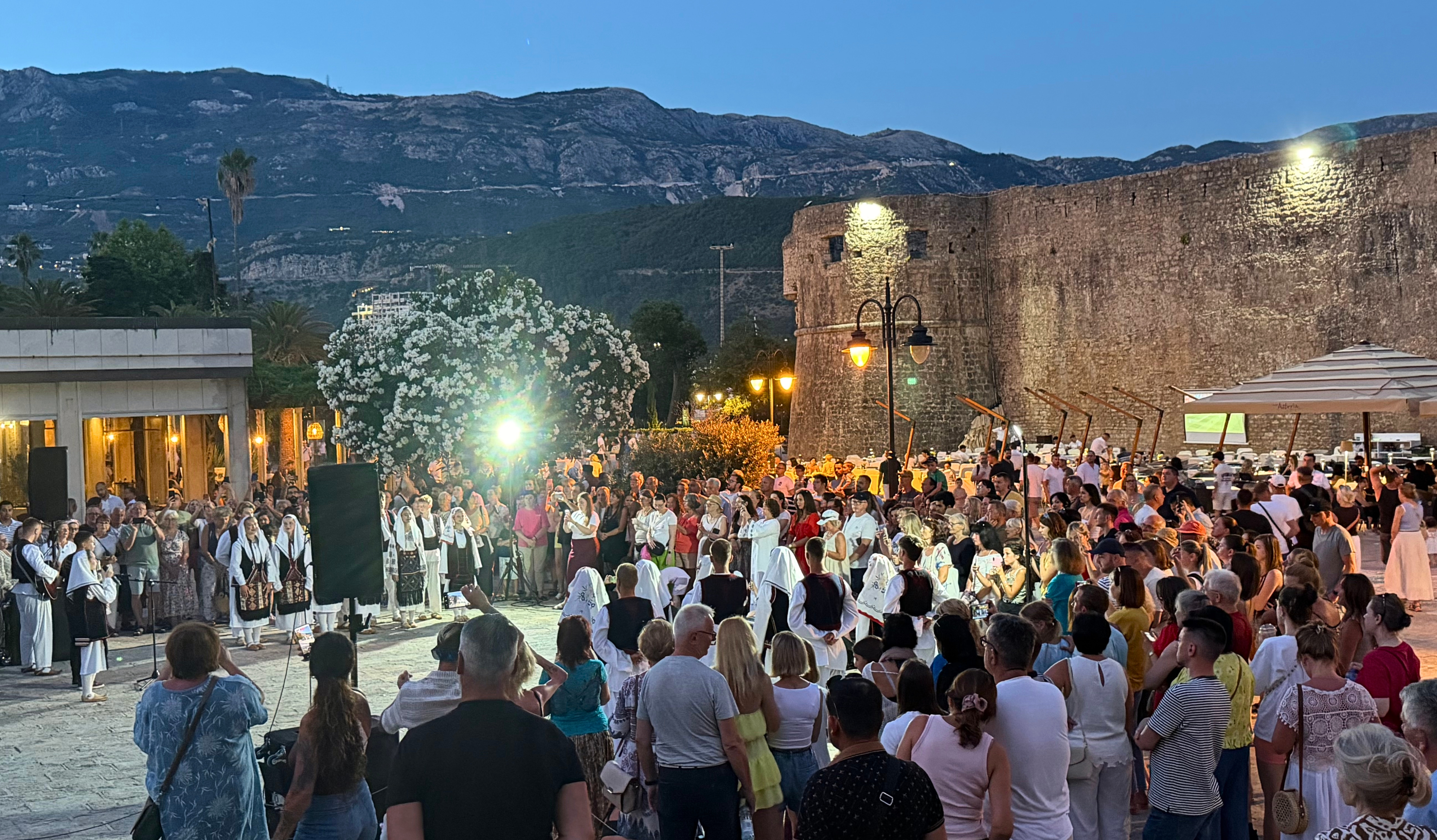 Evening music in Budva, with traditional dress, local song, and a crowd gathered beside the old walls as the town moved into night