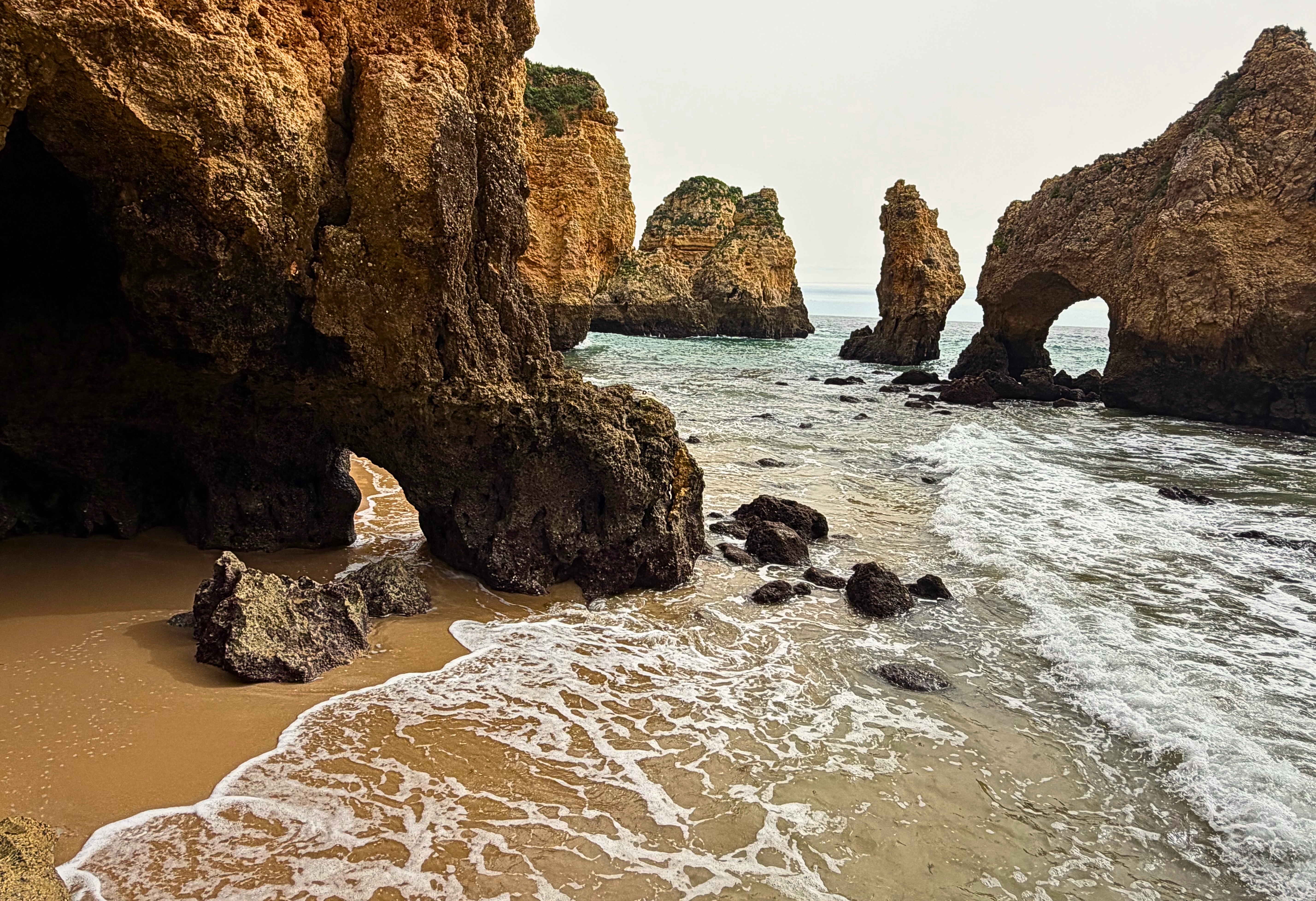 Praia da Dona Ana with golden cliffs, sea arches, and beach coves along the Algarve coast.