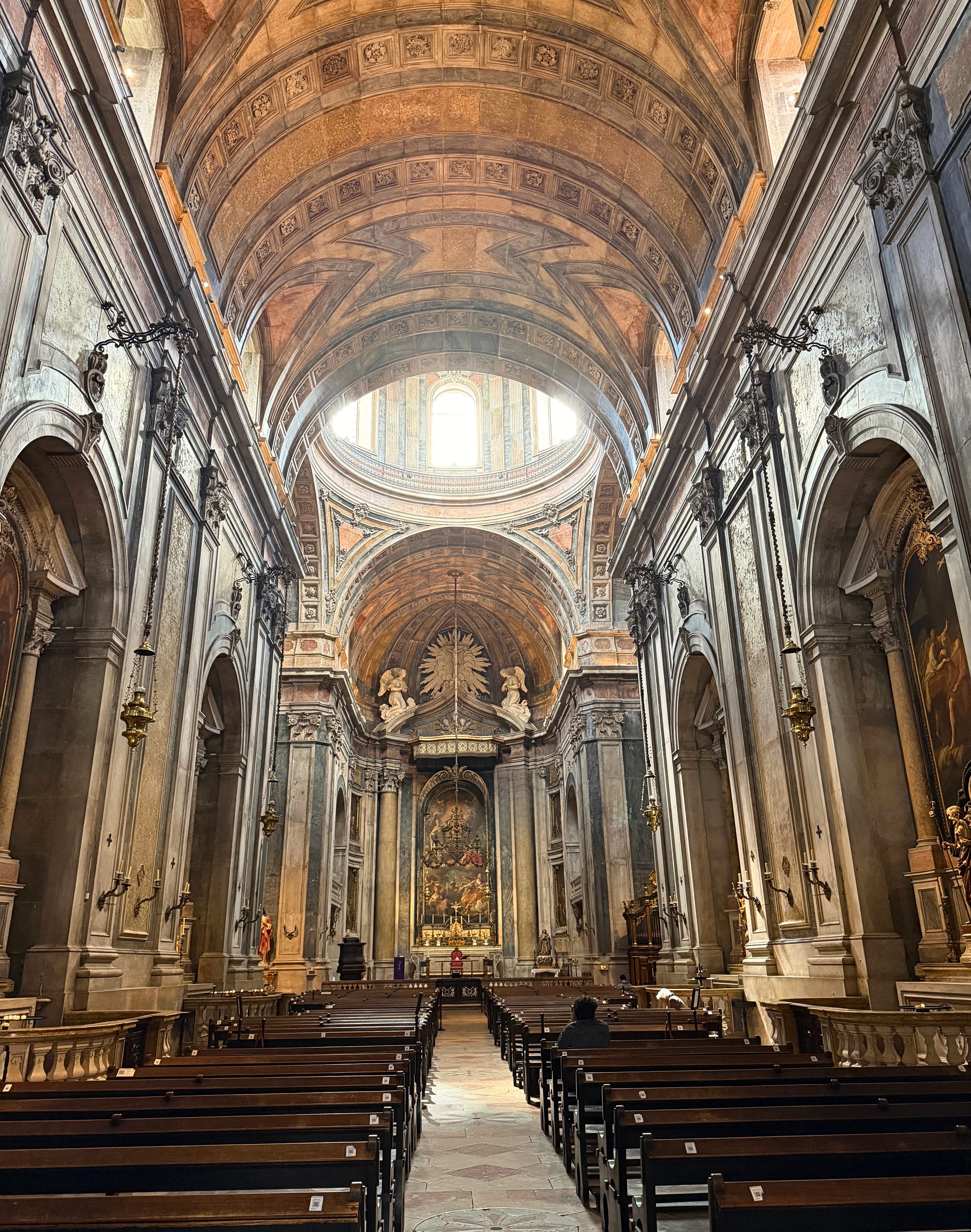 The interior of Basilica da Estrela with ornate stonework and a high vaulted ceiling.