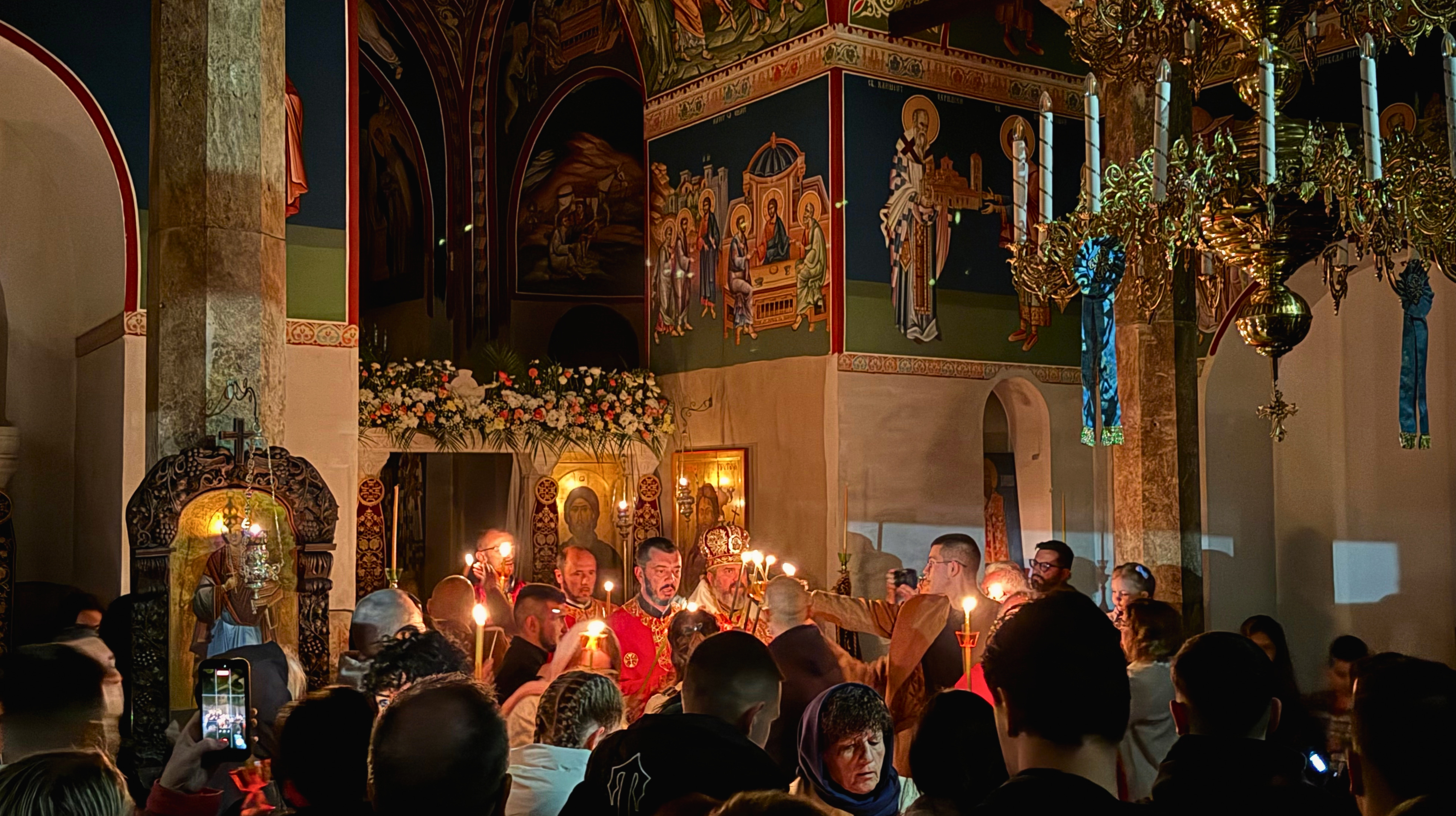 Priests and worshippers holding candles inside the Orthodox Easter service at Plaošnik.