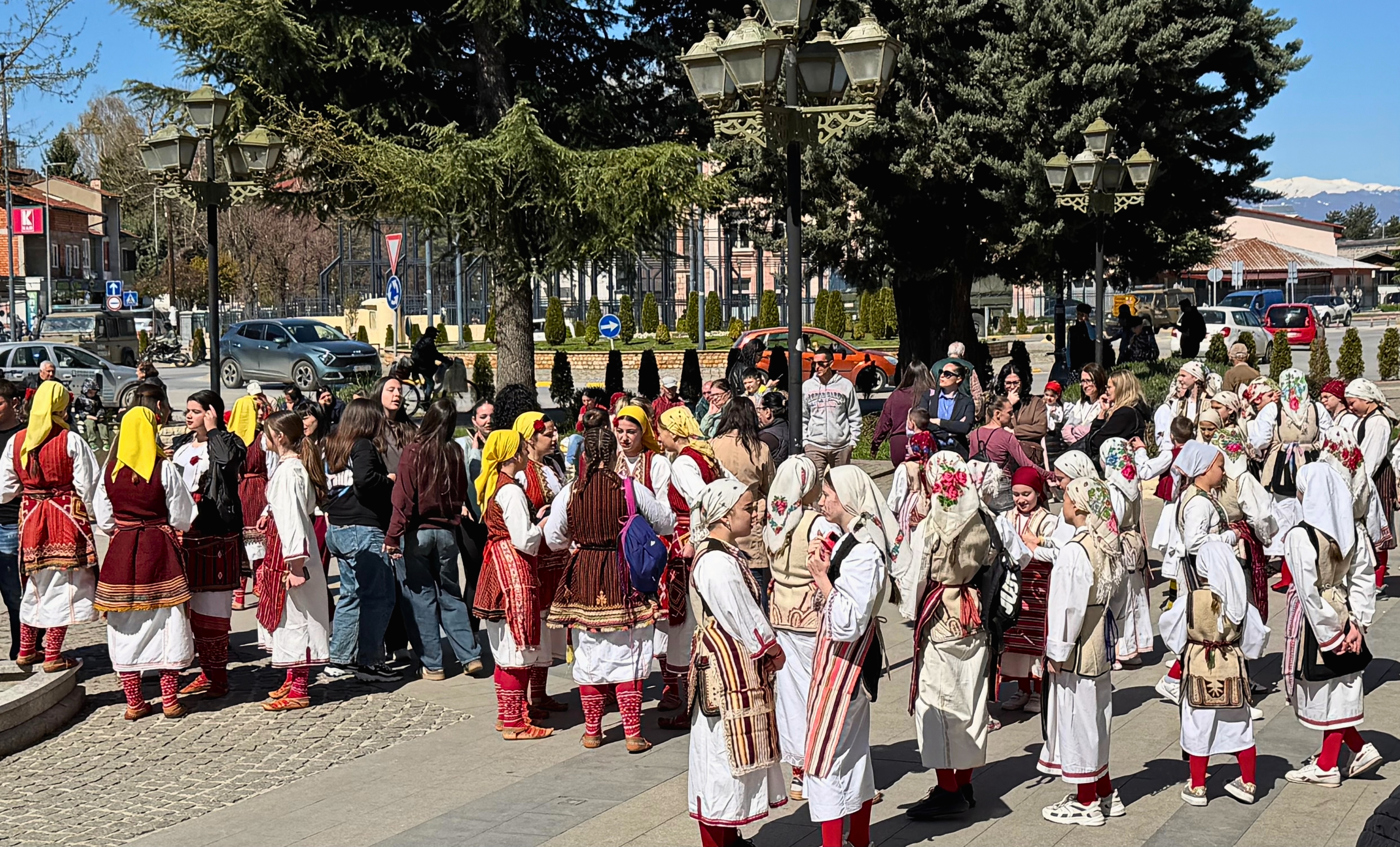 Children and adults in traditional dress gathered in a public square in Ohrid.