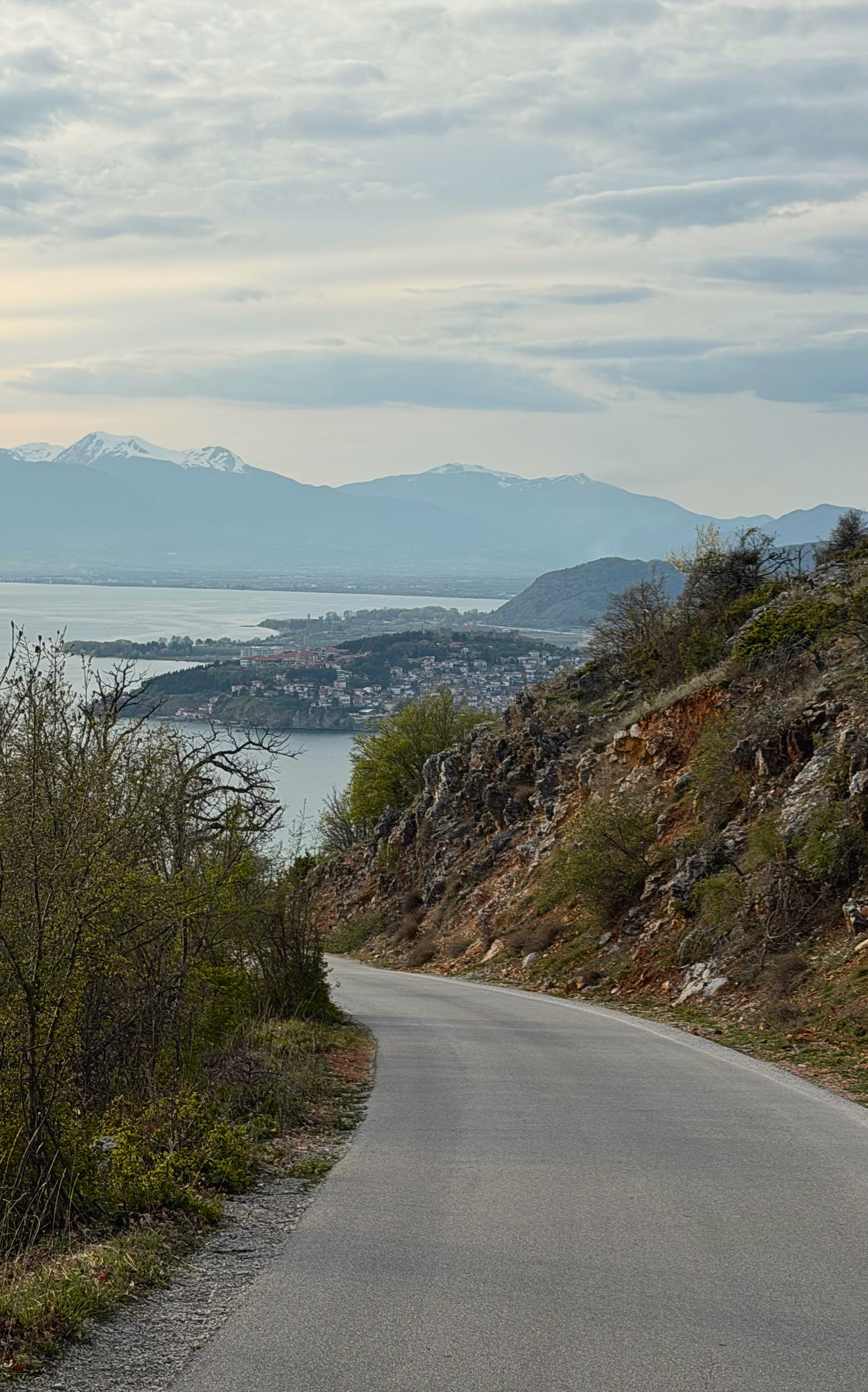 A mountain road descending toward Lake Ohrid with mountains in the distance.