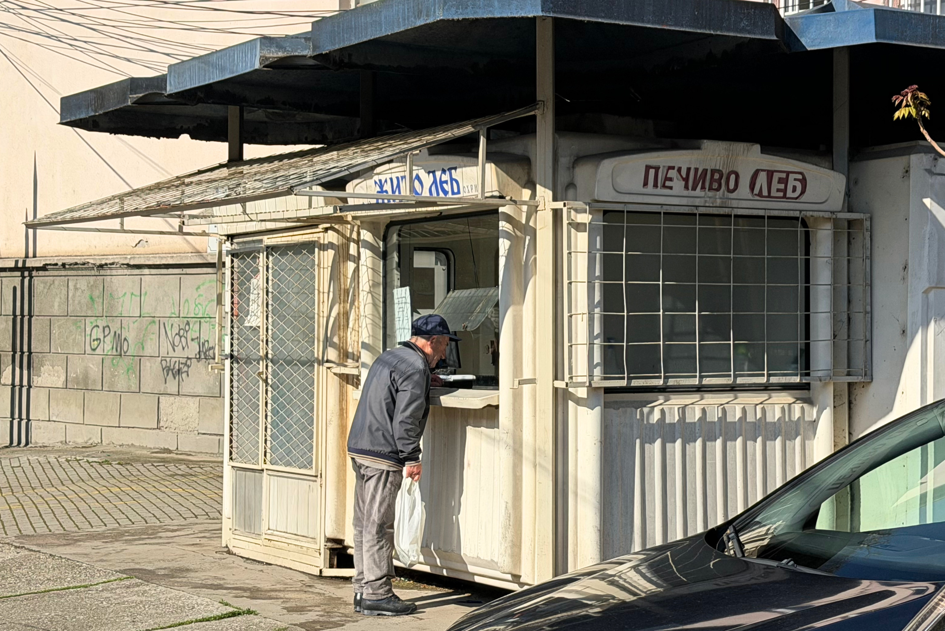 A man buying bread from a small neighborhood bread kiosk in Ohrid.