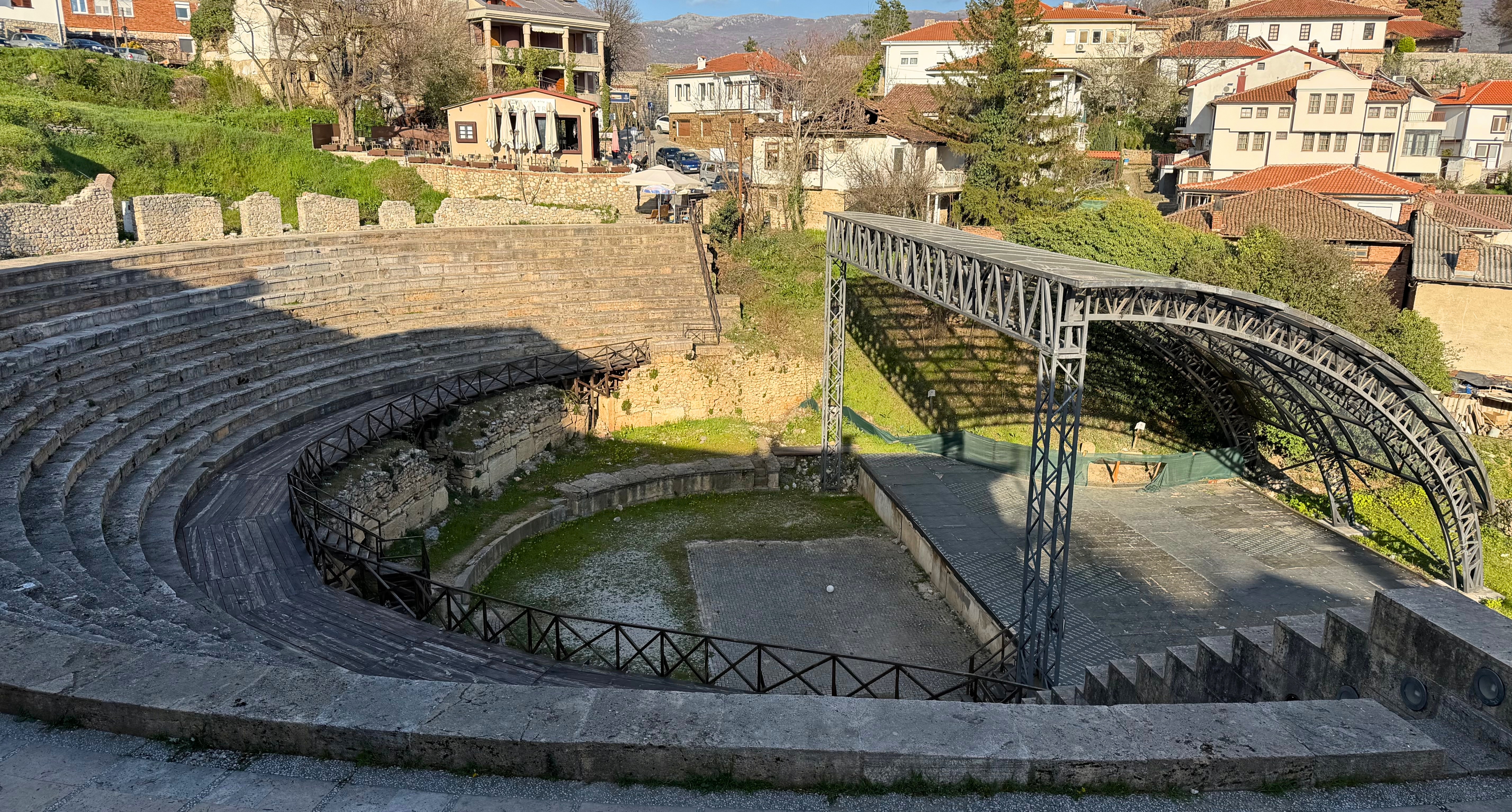 The Ancient Theatre of Ohrid with stone seating and the old town rising behind it.