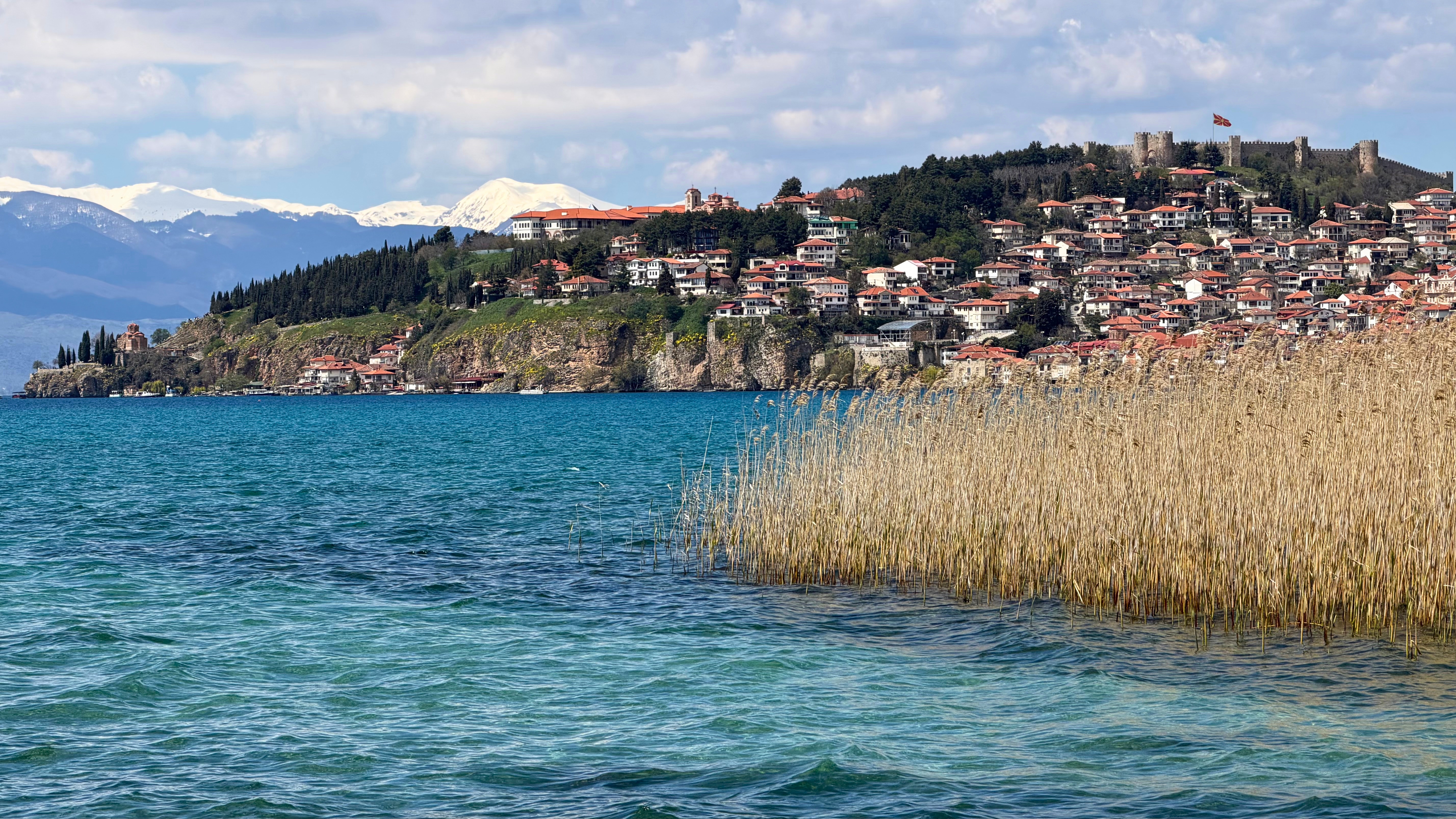 A calm view of Lake Ohrid with blue water and mountains in the distance.