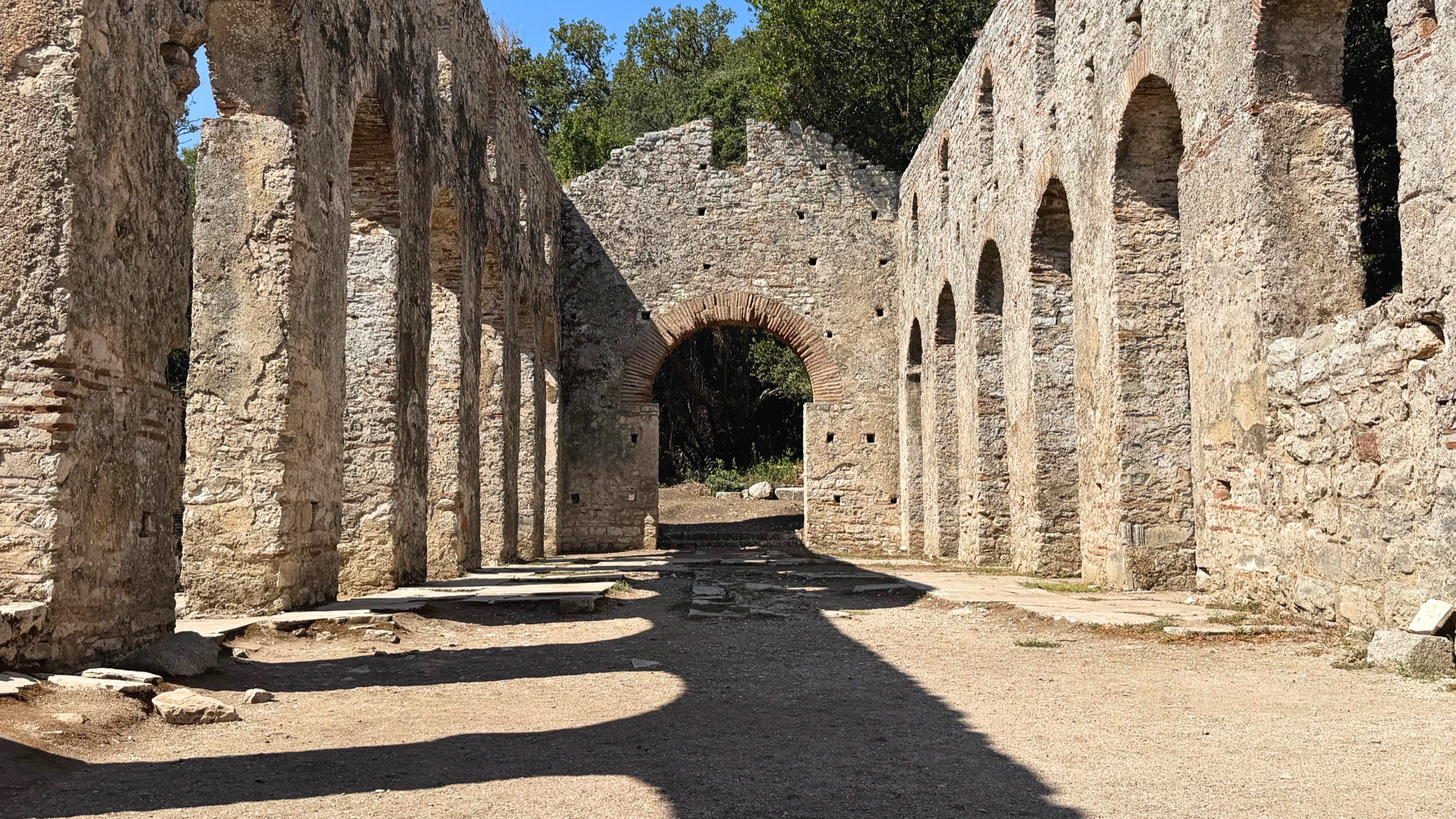 Stone arches and walls inside Butrint's Great Basilica.