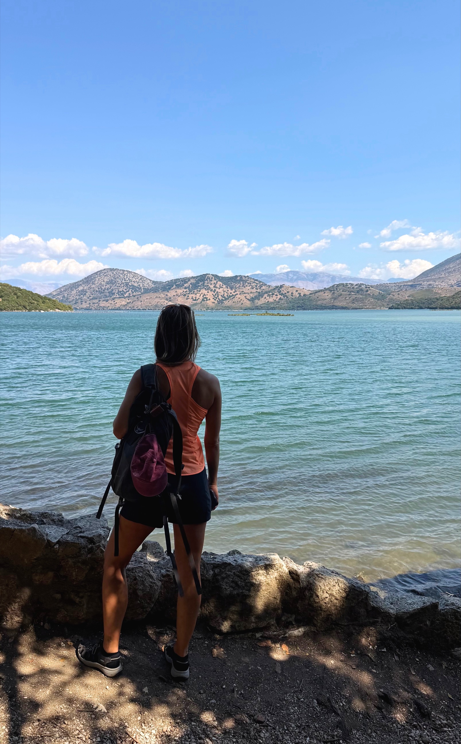 Stephanie standing along Lake Butrint with the water and southern Albanian mountains beyond.