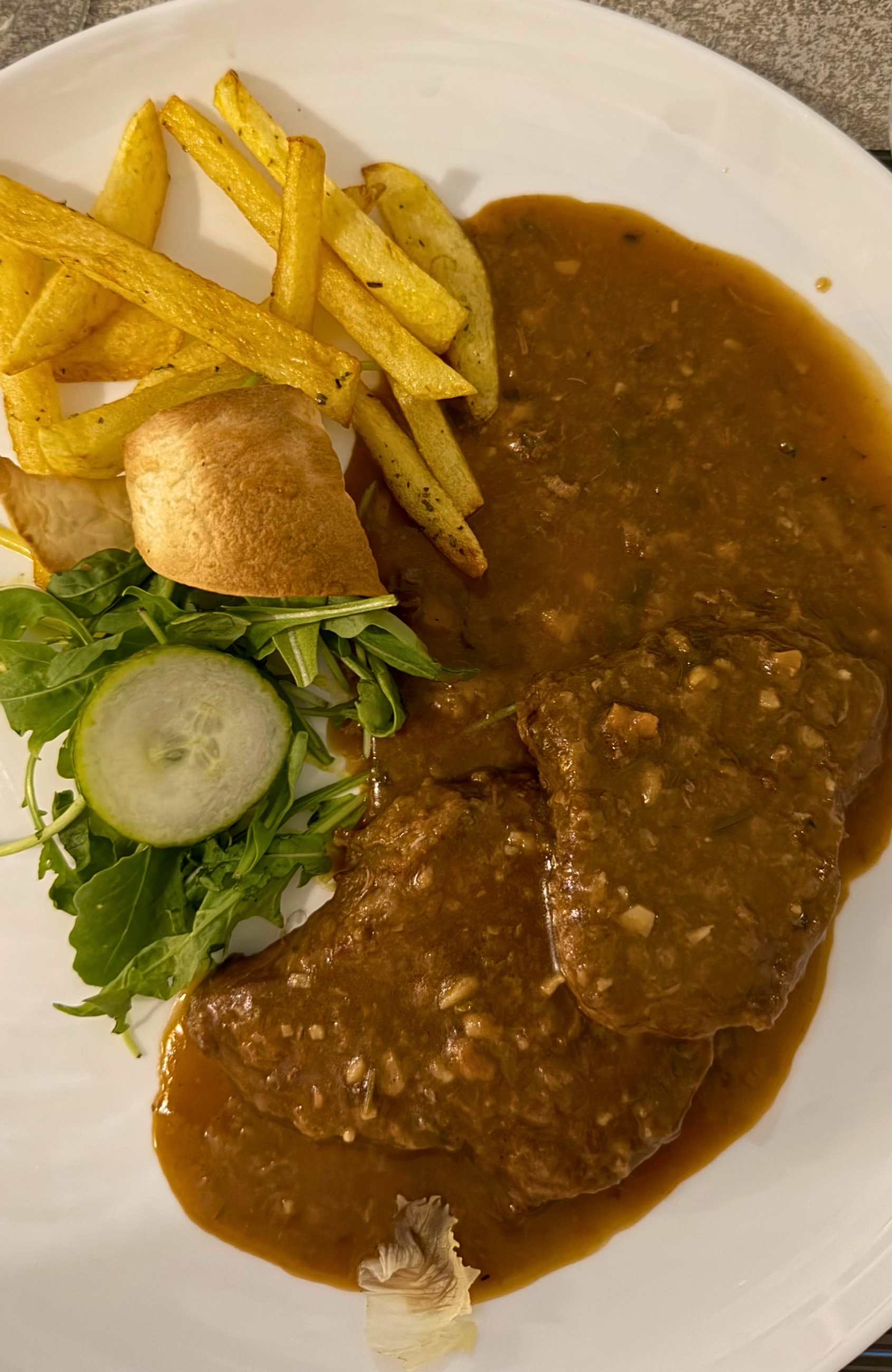 A plate of Corfiot sofrito with slow-cooked veal, sauce, potatoes, bread, and greens.