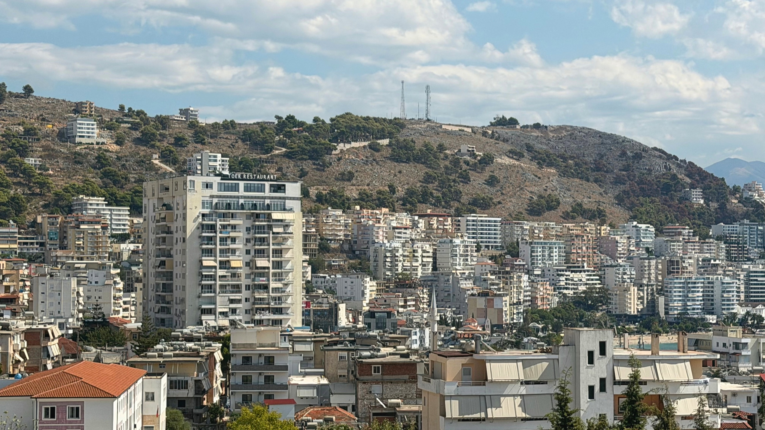 Sarandë apartment buildings and the winding hillside leading toward the Monastery of the Forty Saints.