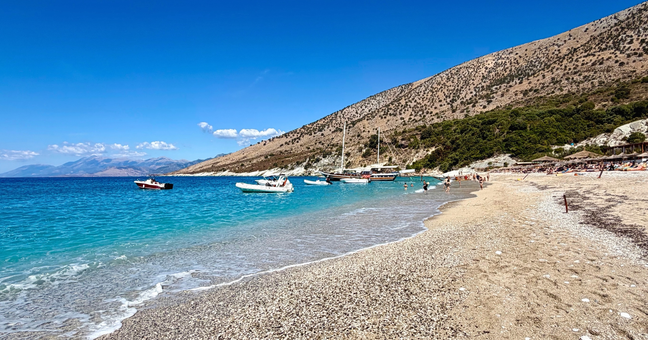 Krorëza Beach and turquoise water beneath dry coastal hills.