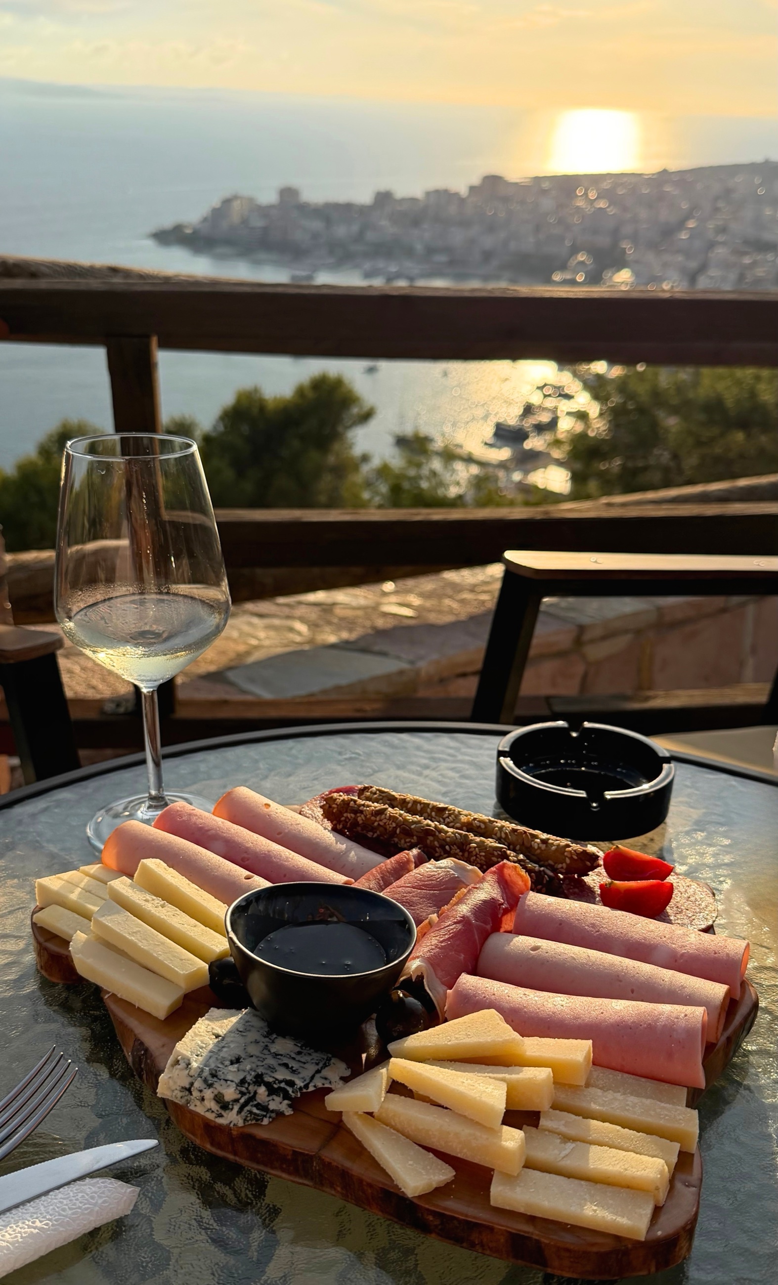 Wine and charcuterie on a terrace table overlooking Sarandë Bay.