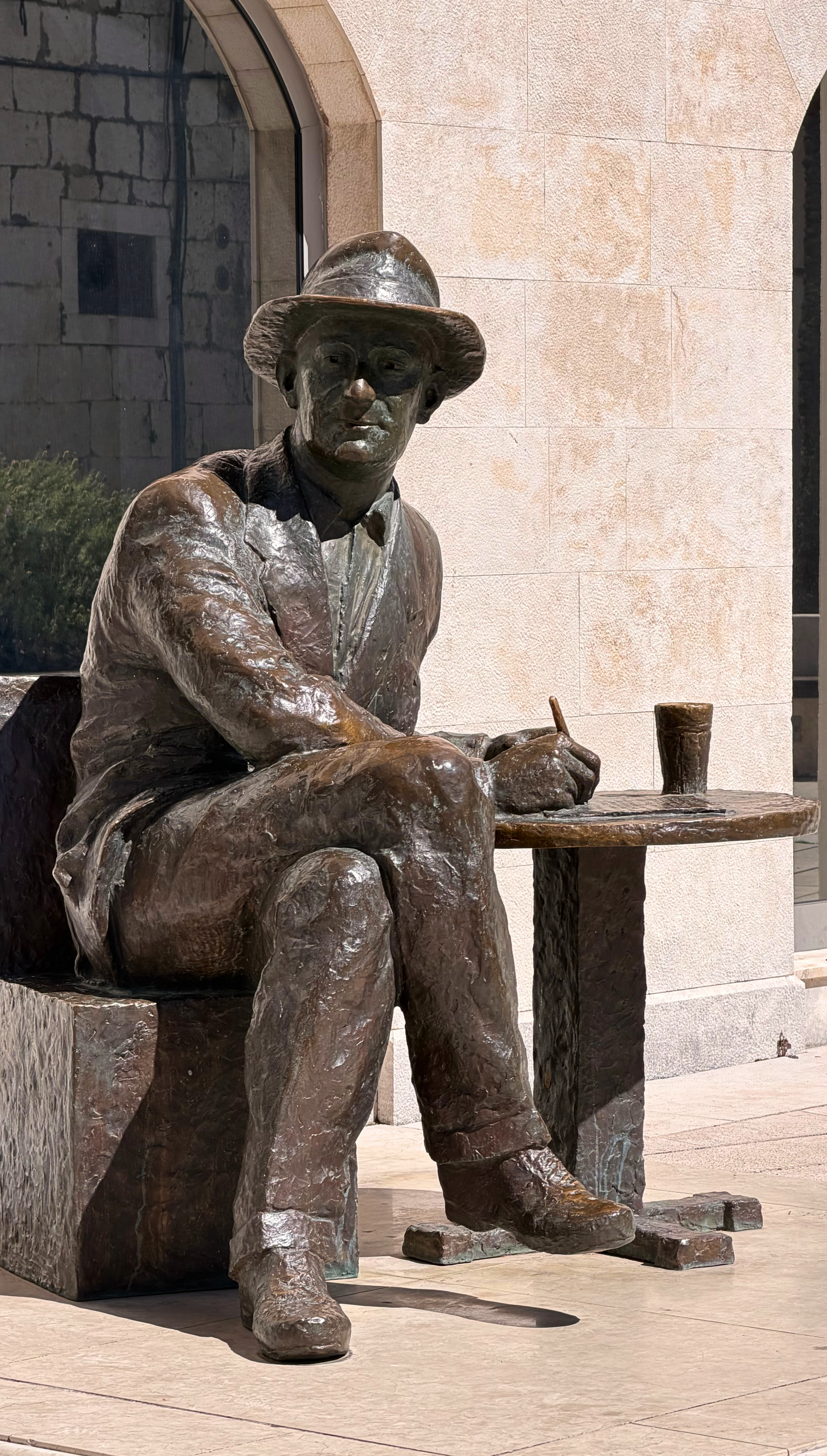 Bronze statue of Croatian poet Tin Ujević seated at a small table in Makarska
