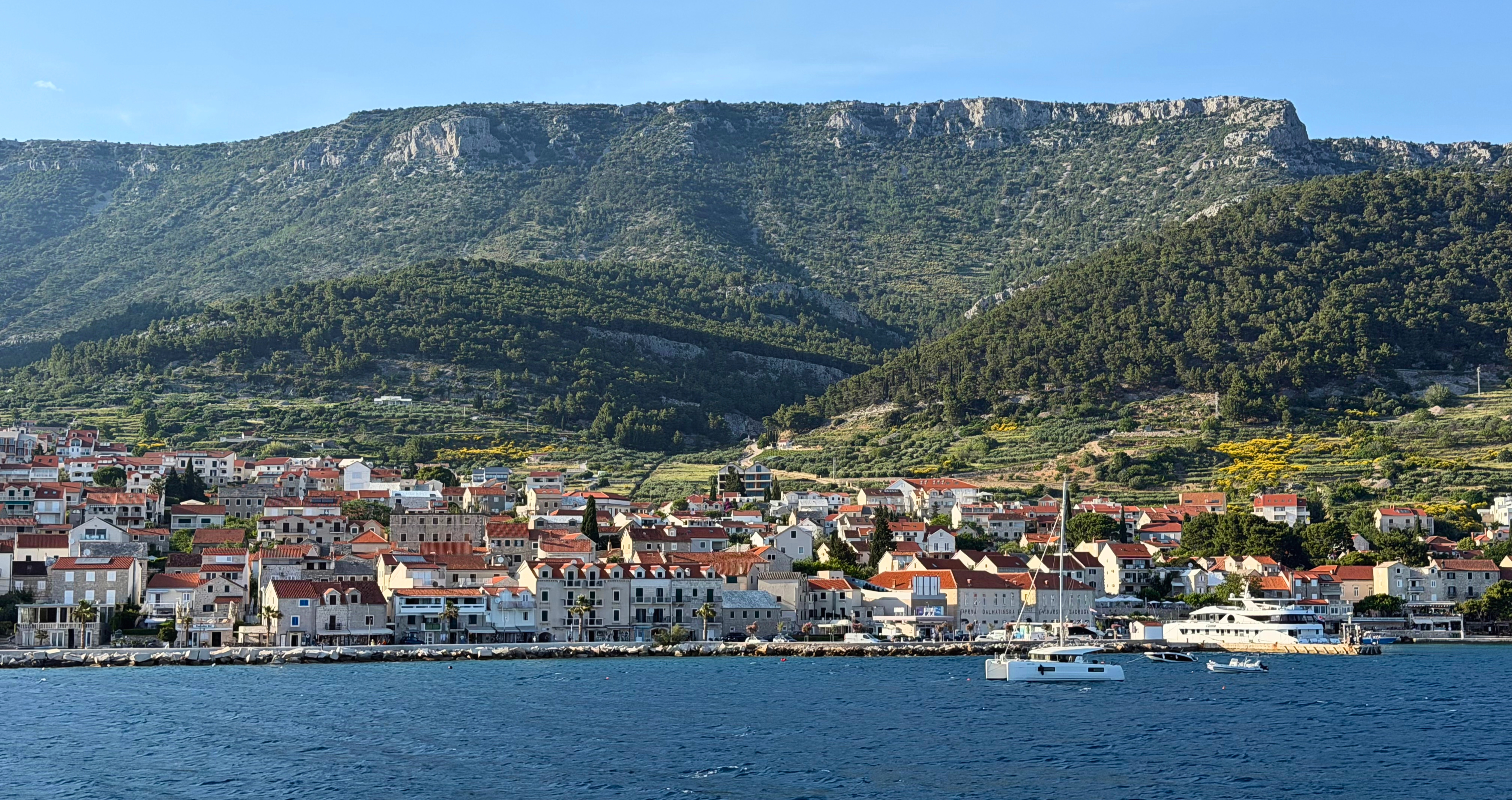 Bol on Brač viewed from the water with green slopes behind the town