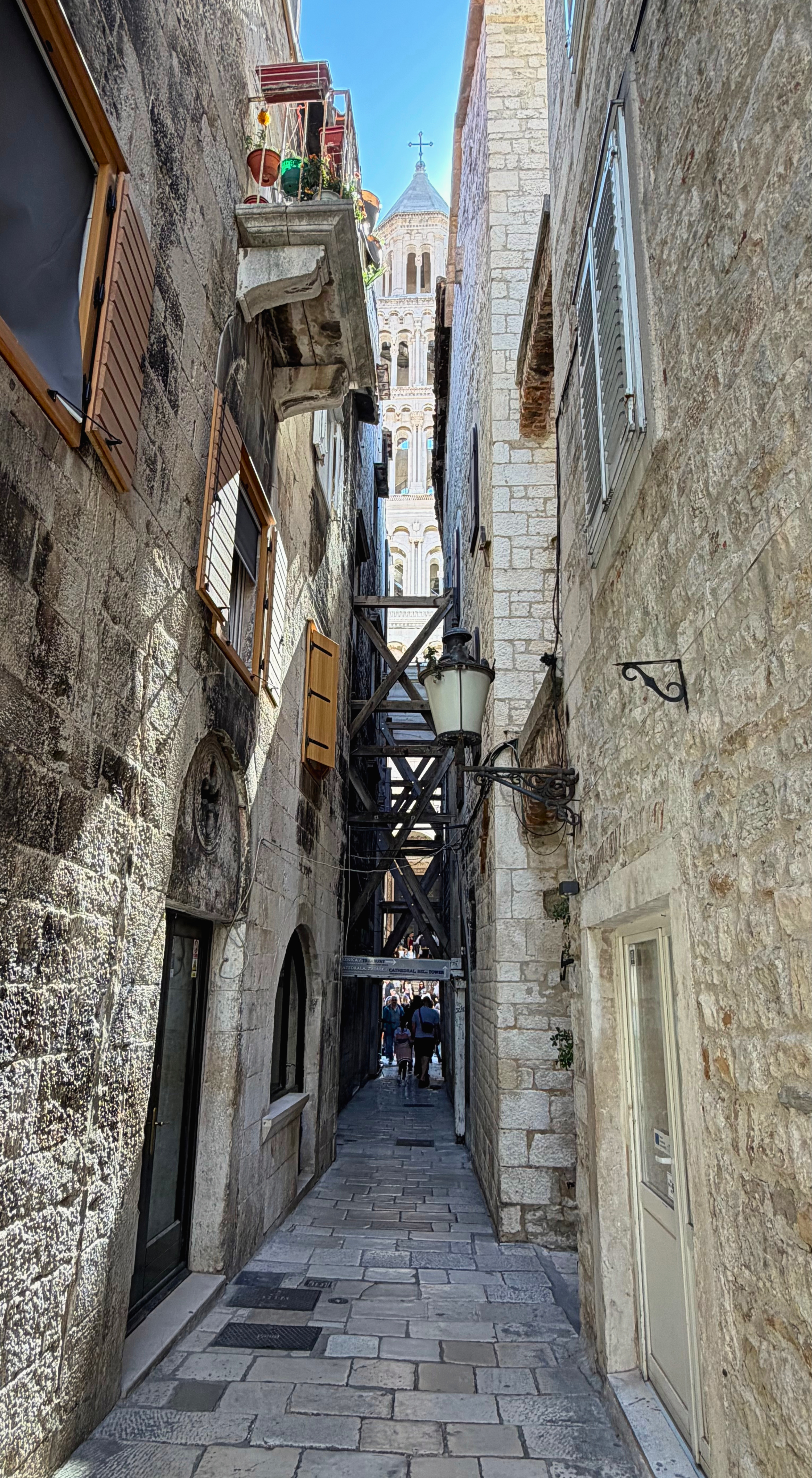 A narrow Split stone lane with the cathedral tower visible between old buildings.