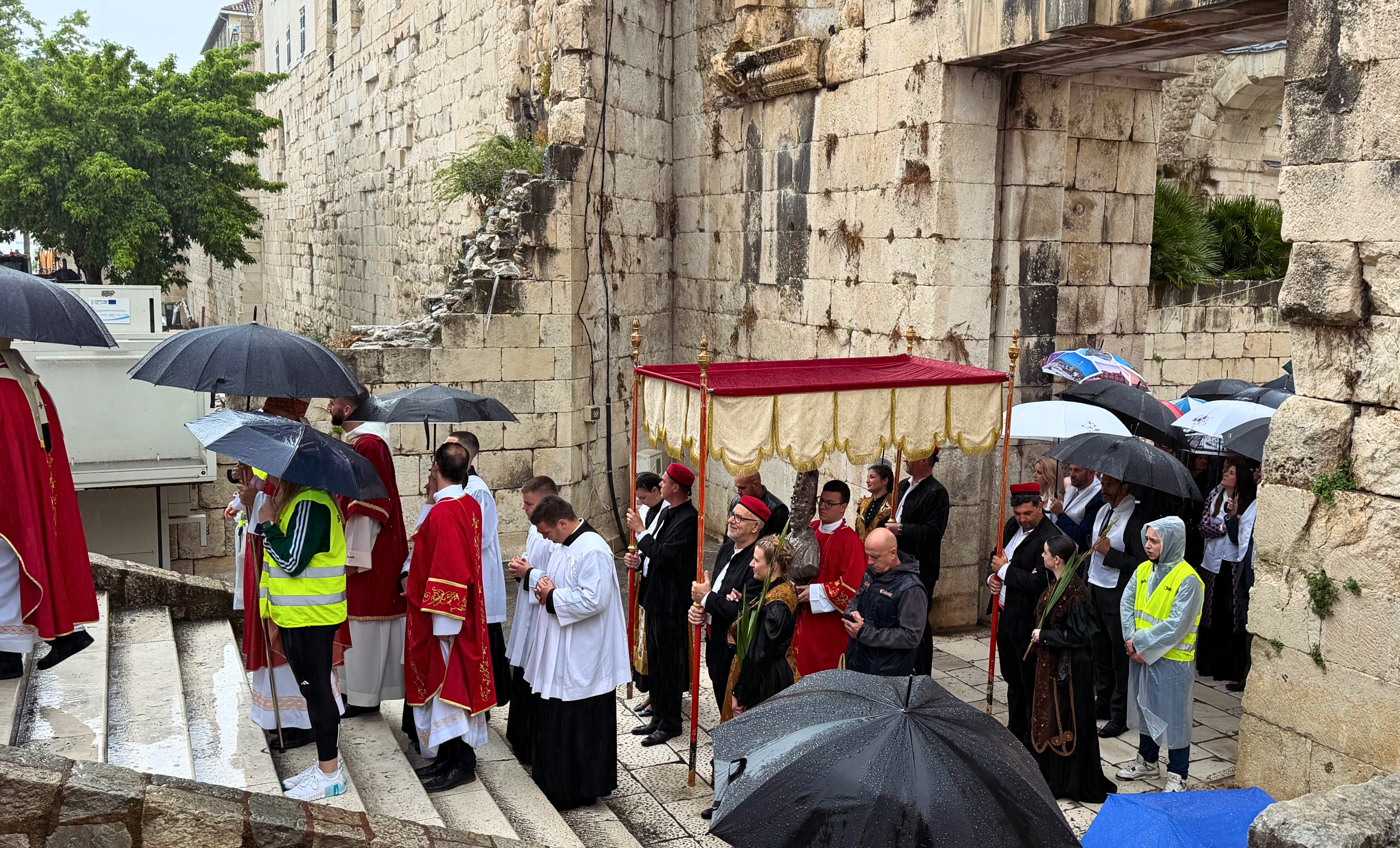Saint Domnius procession moving through an old gate in Diocletian’s Palace during rain