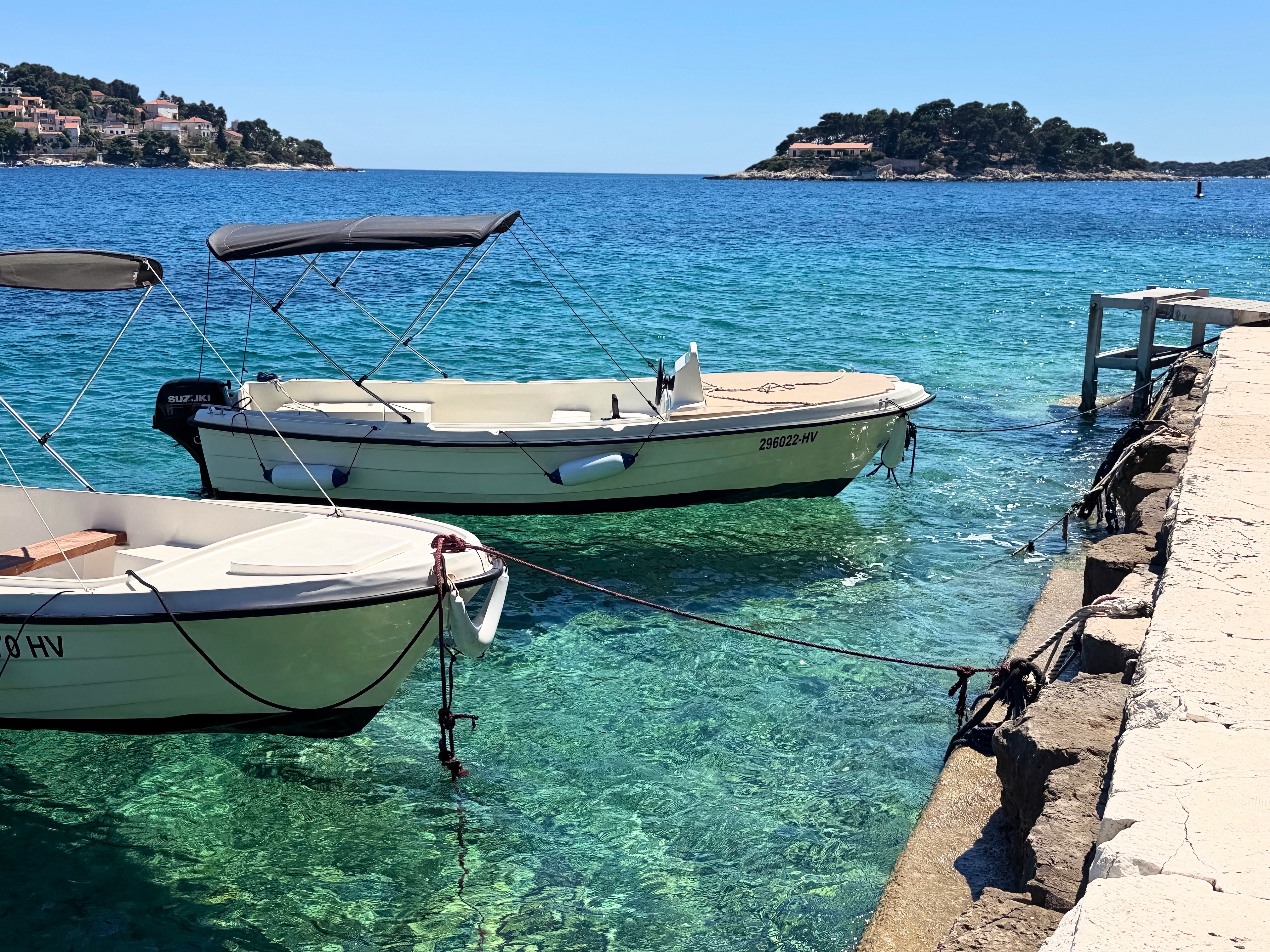 Small boats floating in clear Adriatic water beside the Hvar waterfront