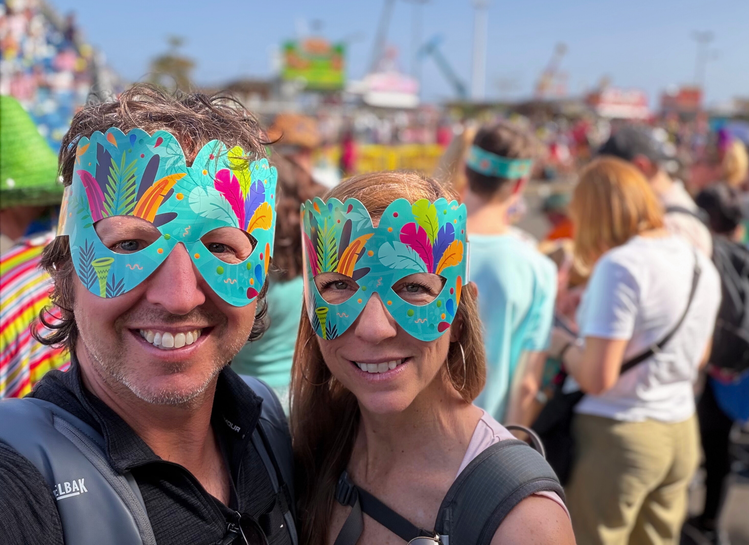 Sam and Stephanie wearing Carnival masks in the crowd at Santa Cruz Carnival.