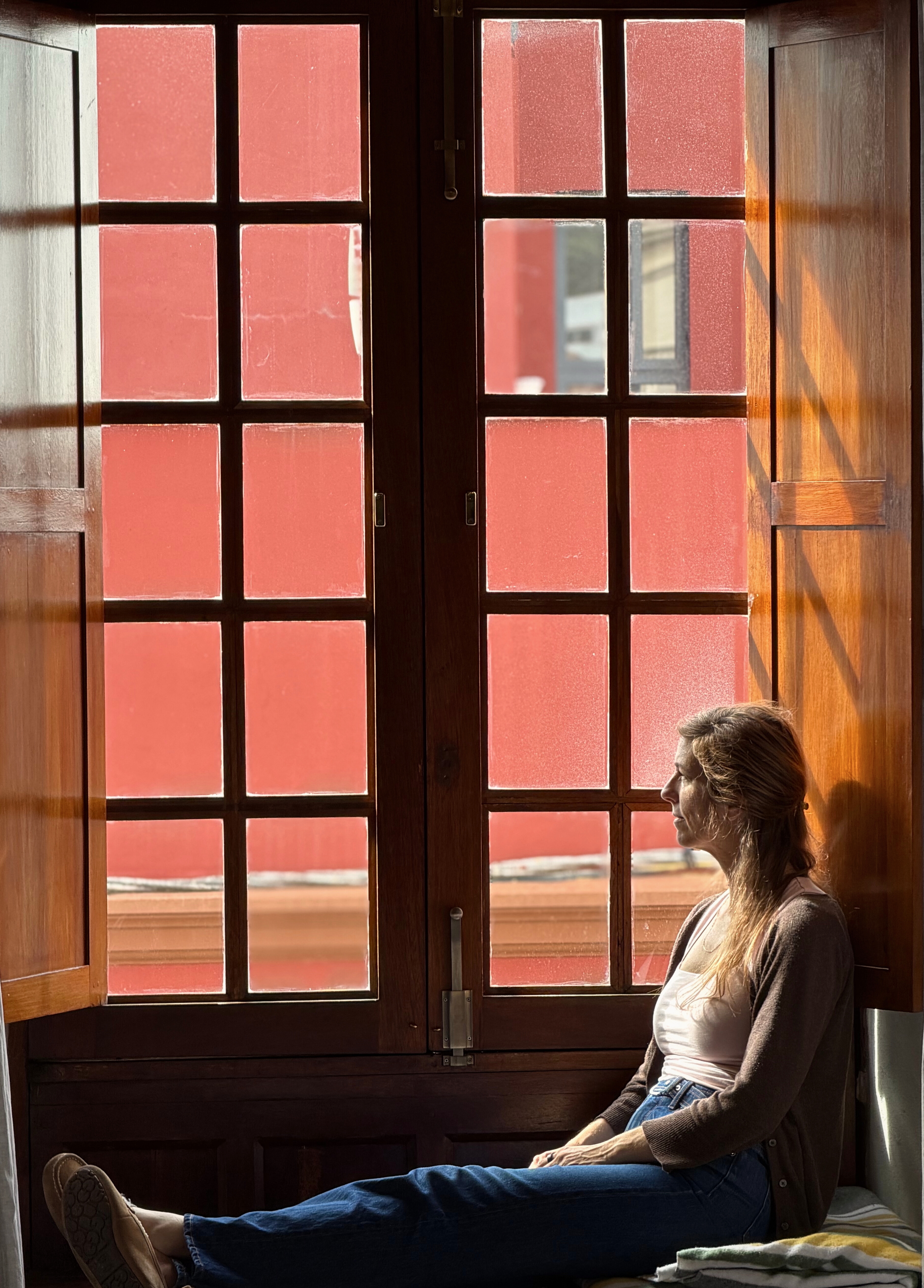 Stephanie sitting beside a tall wooden window in the second La Laguna apartment.