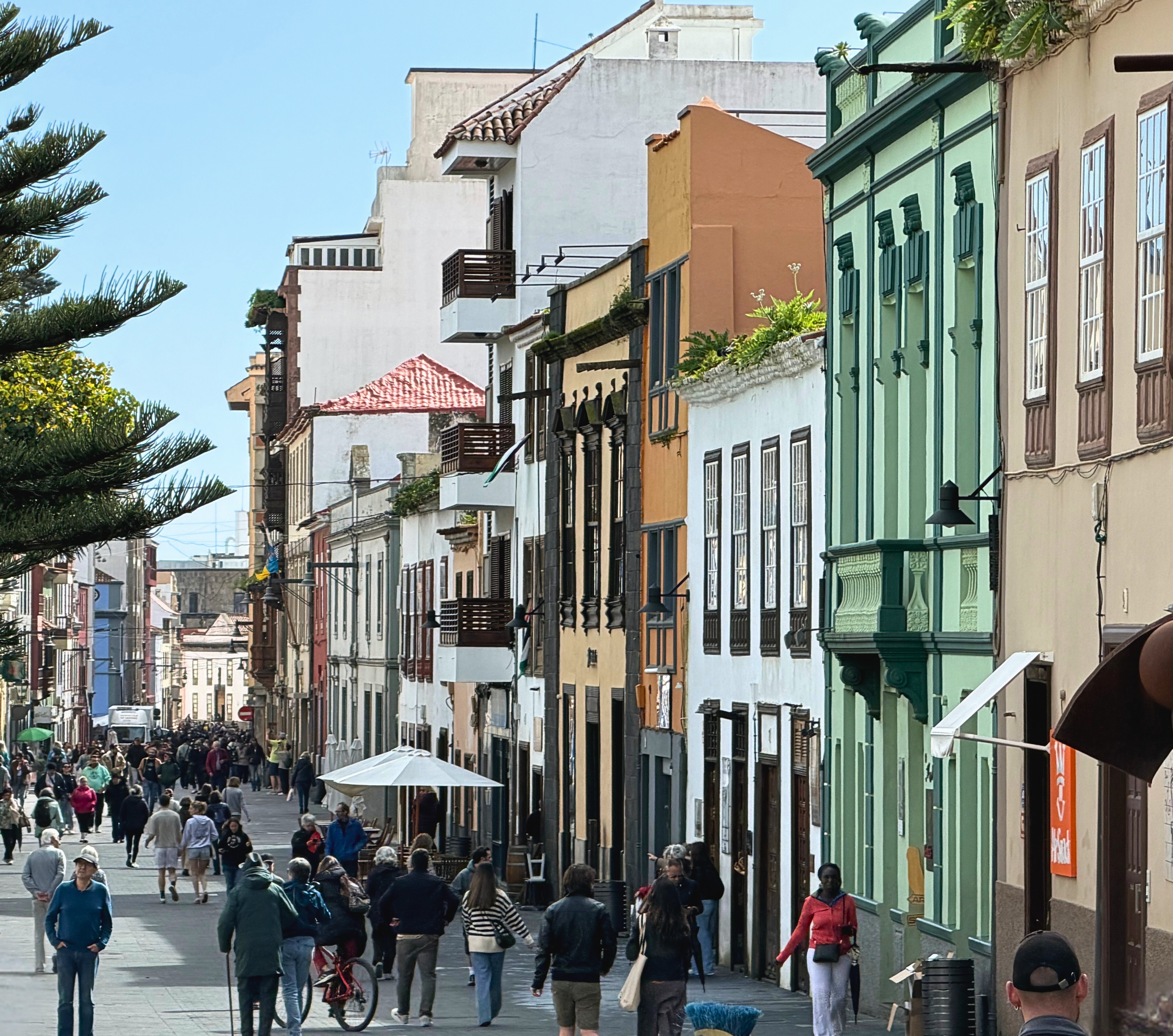 A busy pedestrian street in La Laguna lined with colorful historic buildings.