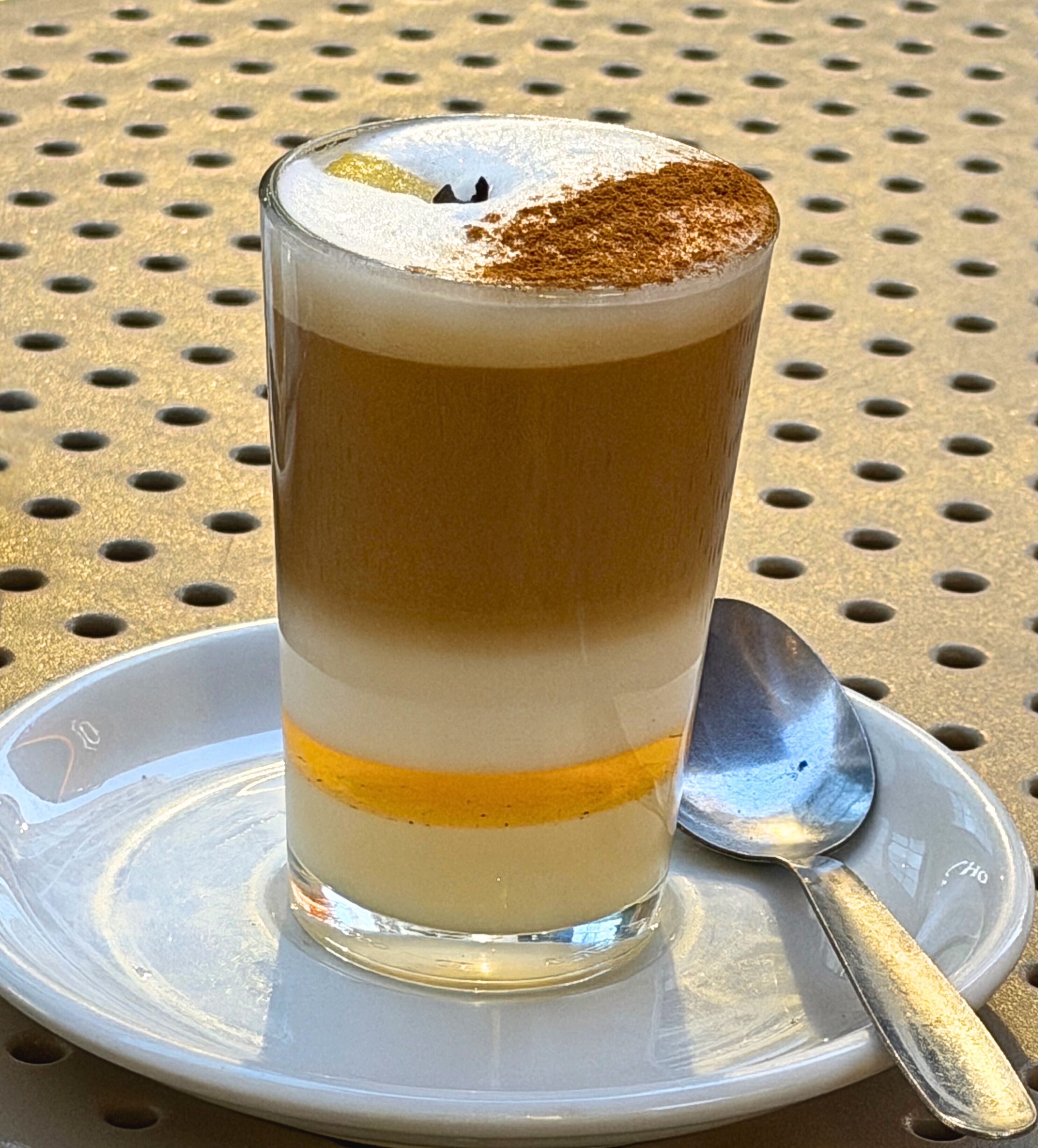 A layered barraquito coffee in a small glass on a café table.