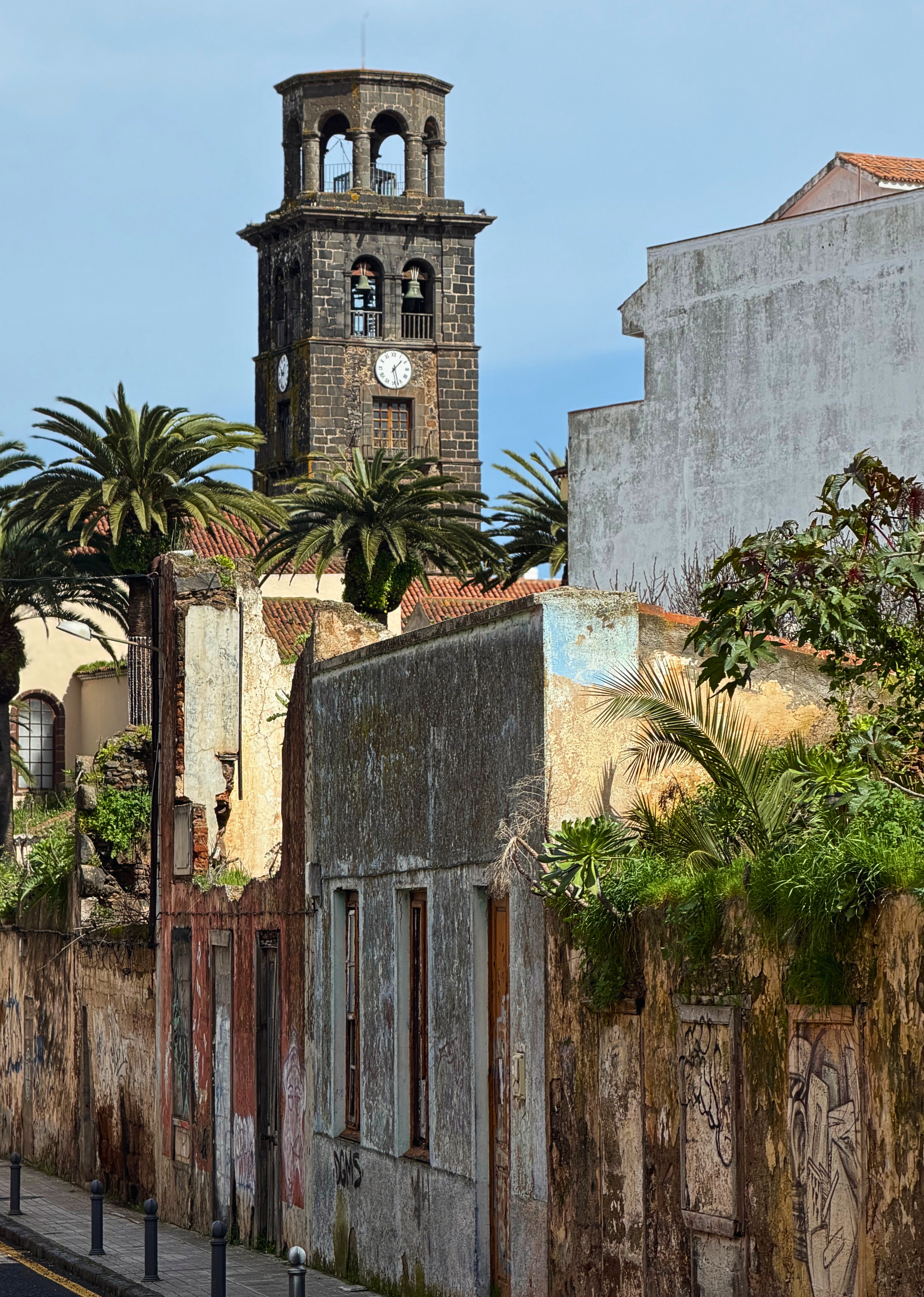 A weathered street corner in La Laguna with the church tower in the background.