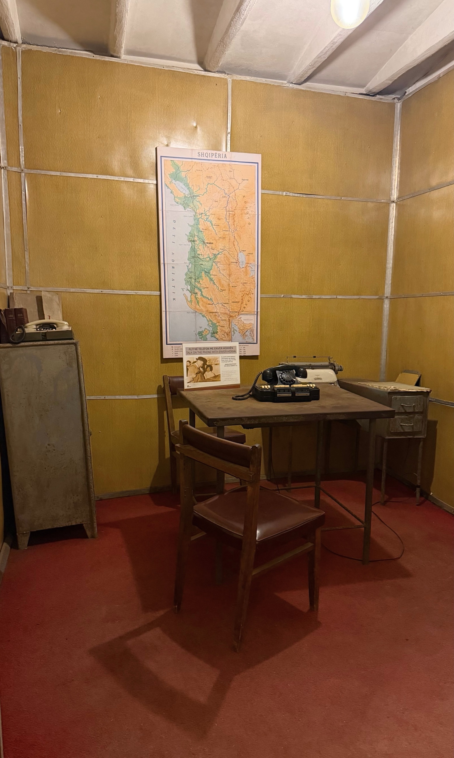 Enver Hoxha's underground office at Bunk'Art 1, with a desk, telephone, typewriter, map of Albania, and simple chairs.