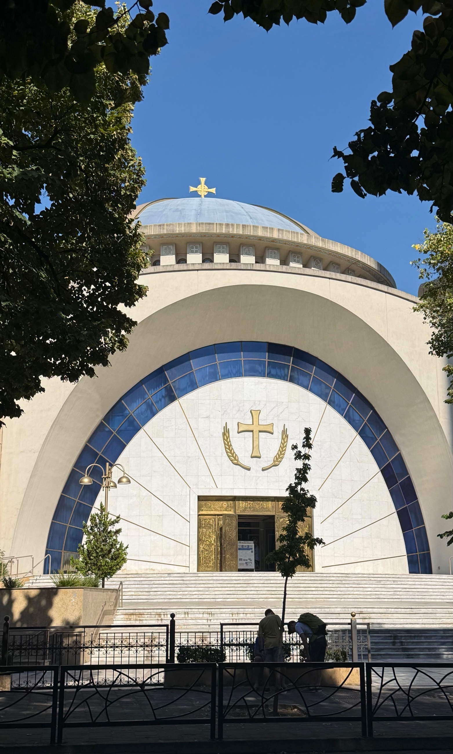 The Resurrection of Christ Orthodox Cathedral in central Tirana, framed by trees beneath a clear blue sky.