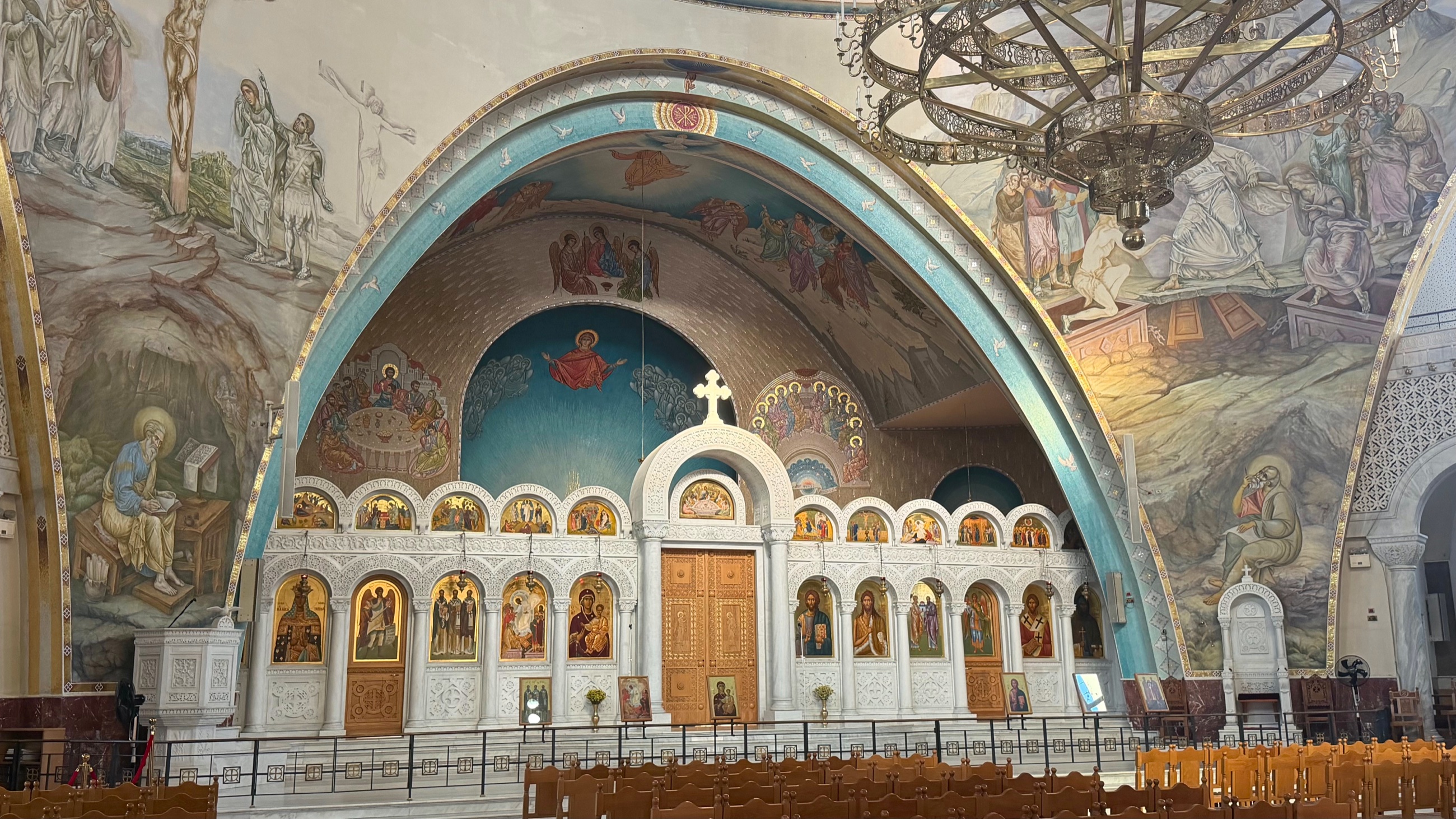 The richly decorated interior of Tirana's Resurrection of Christ Orthodox Cathedral, with icons and painted biblical scenes.