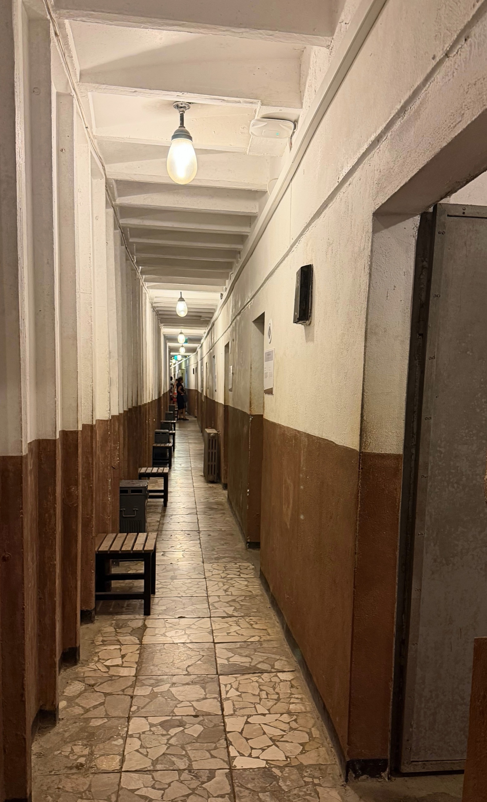 A long underground corridor inside Bunk'Art 1 lined with repeating steel doors and bare overhead lights.