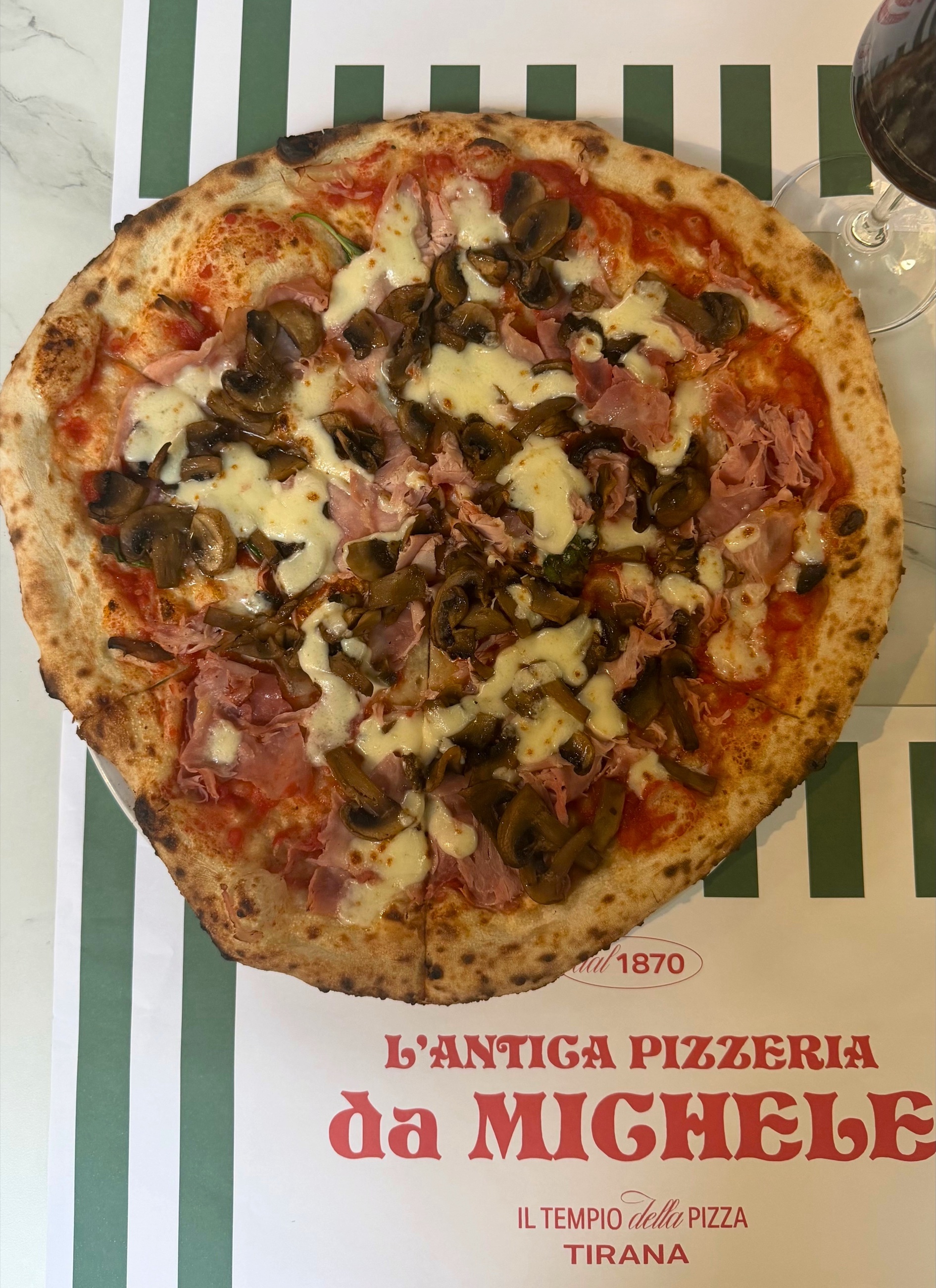 A cotto e funghi pizza with mushrooms, cooked ham, tomato, and cheese at L'Antica Pizzeria da Michele in Tirana.