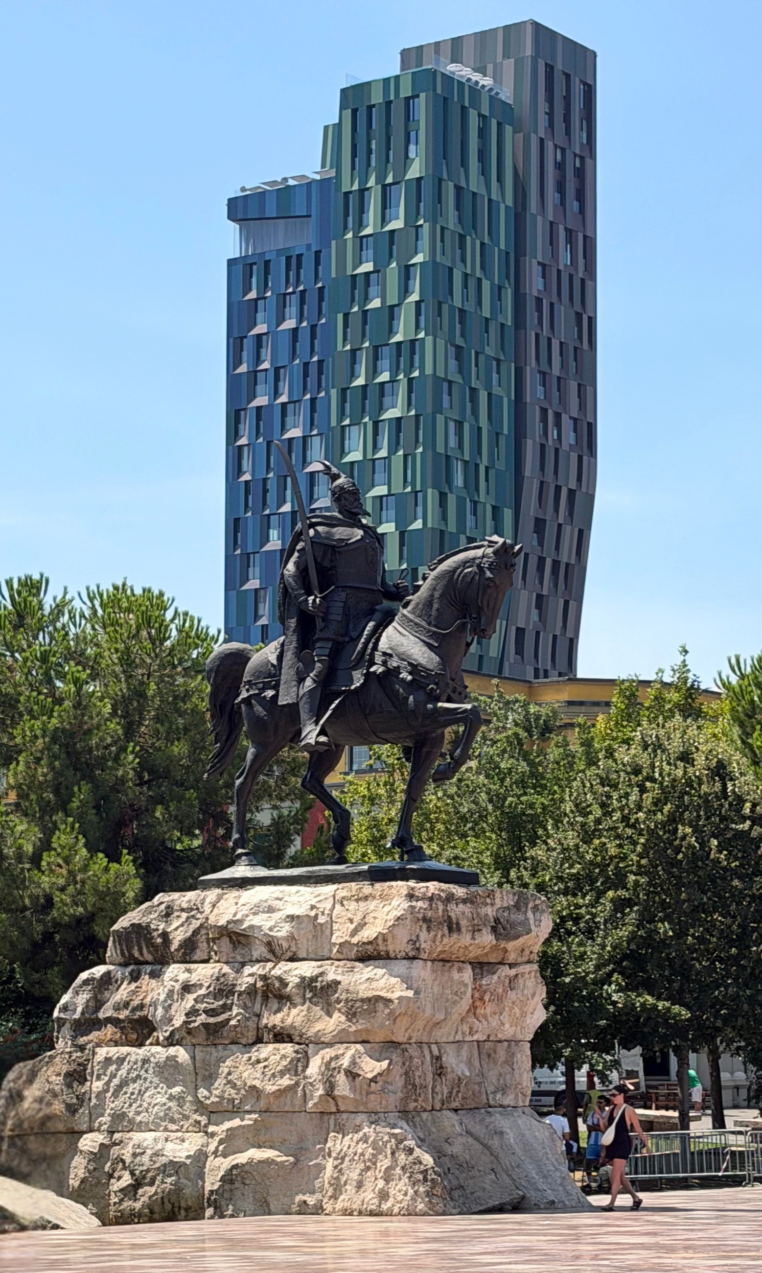 The Skanderbeg Monument in Tirana with a contemporary high-rise behind it.