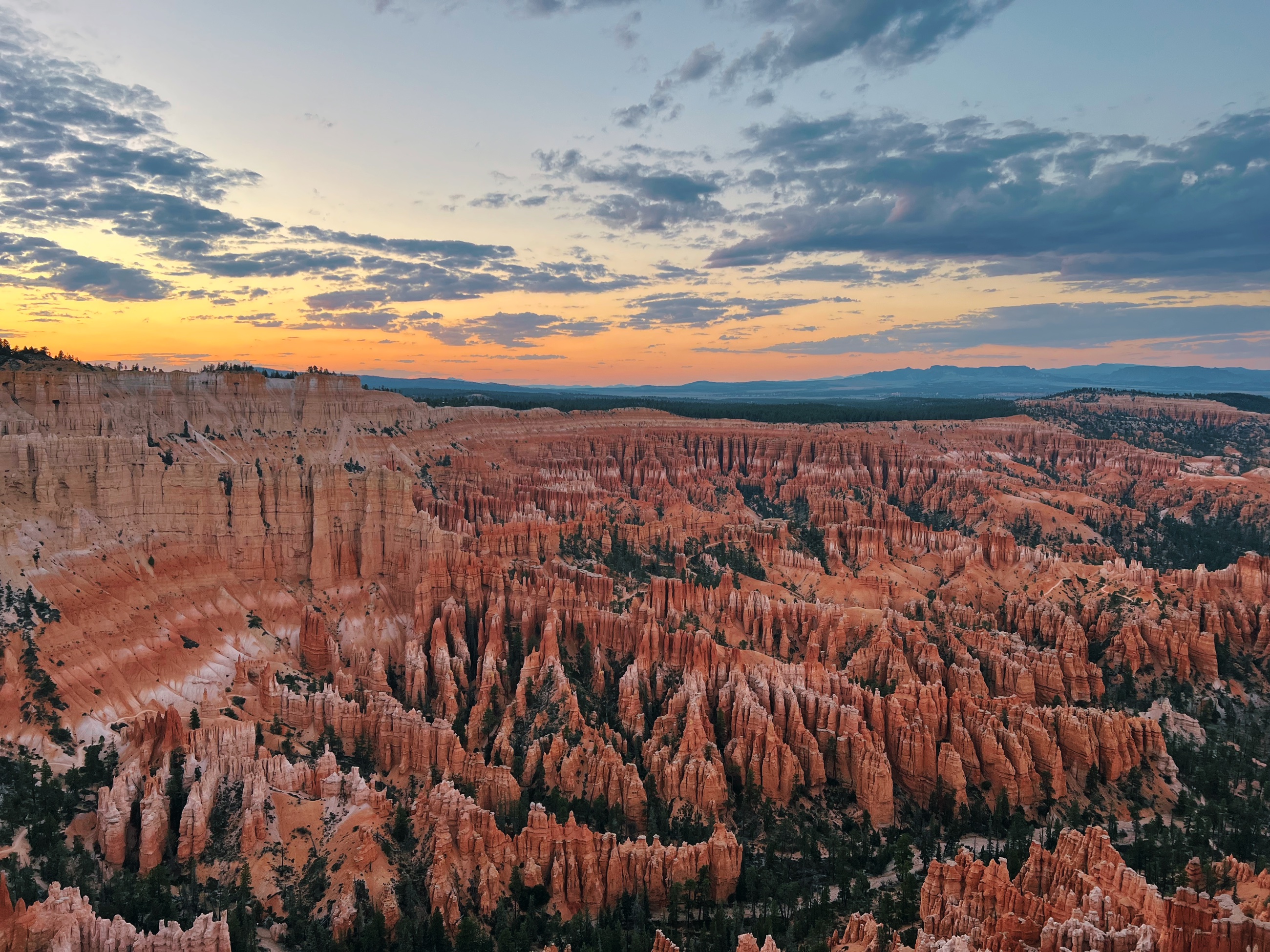Sunset light spreading across the hoodoos and amphitheater at Bryce Point in Bryce Canyon National Park.