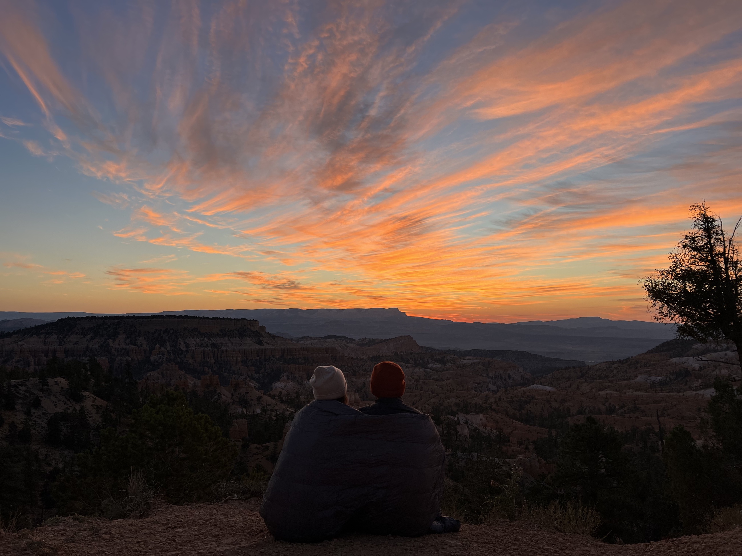 Stephanie sitting near a camp stove and coffee setup at dawn near Bryce Canyon.