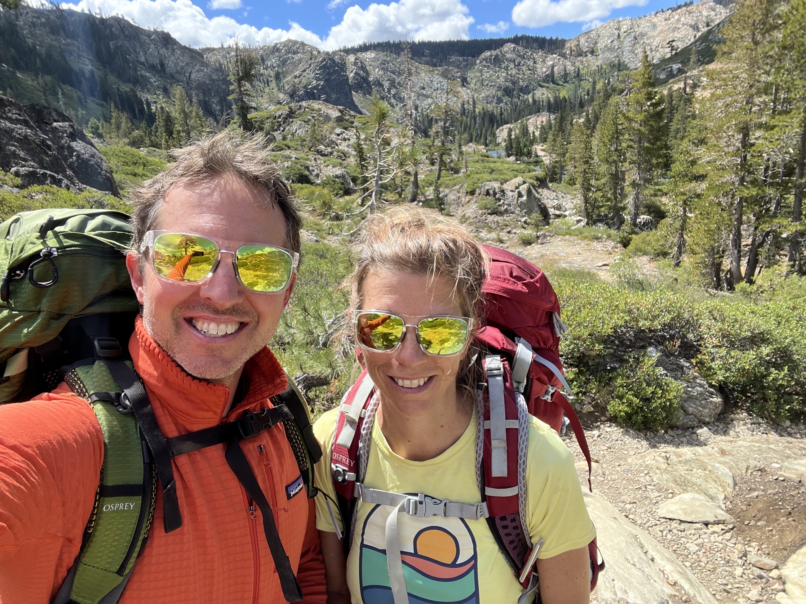 Sam and Stephanie hiking with backpacks on a trail in California's Lakes Basin Recreation Area.