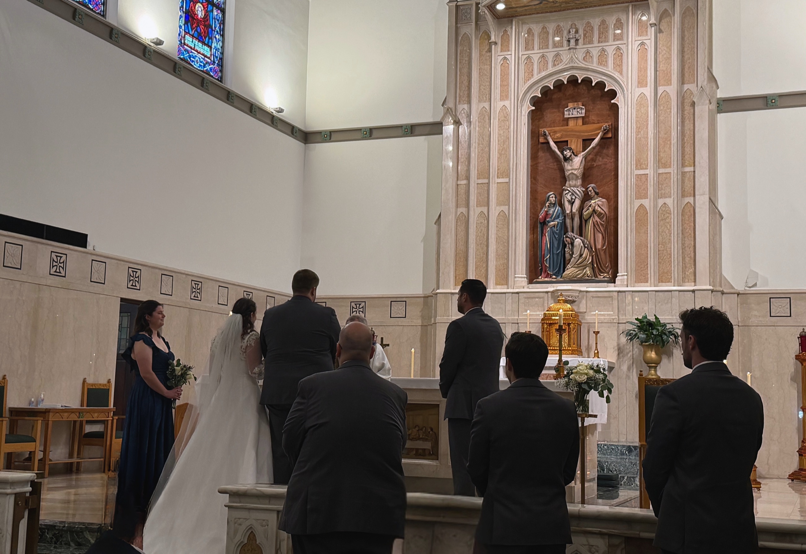 A bride and groom standing at the altar during a Catholic wedding ceremony.