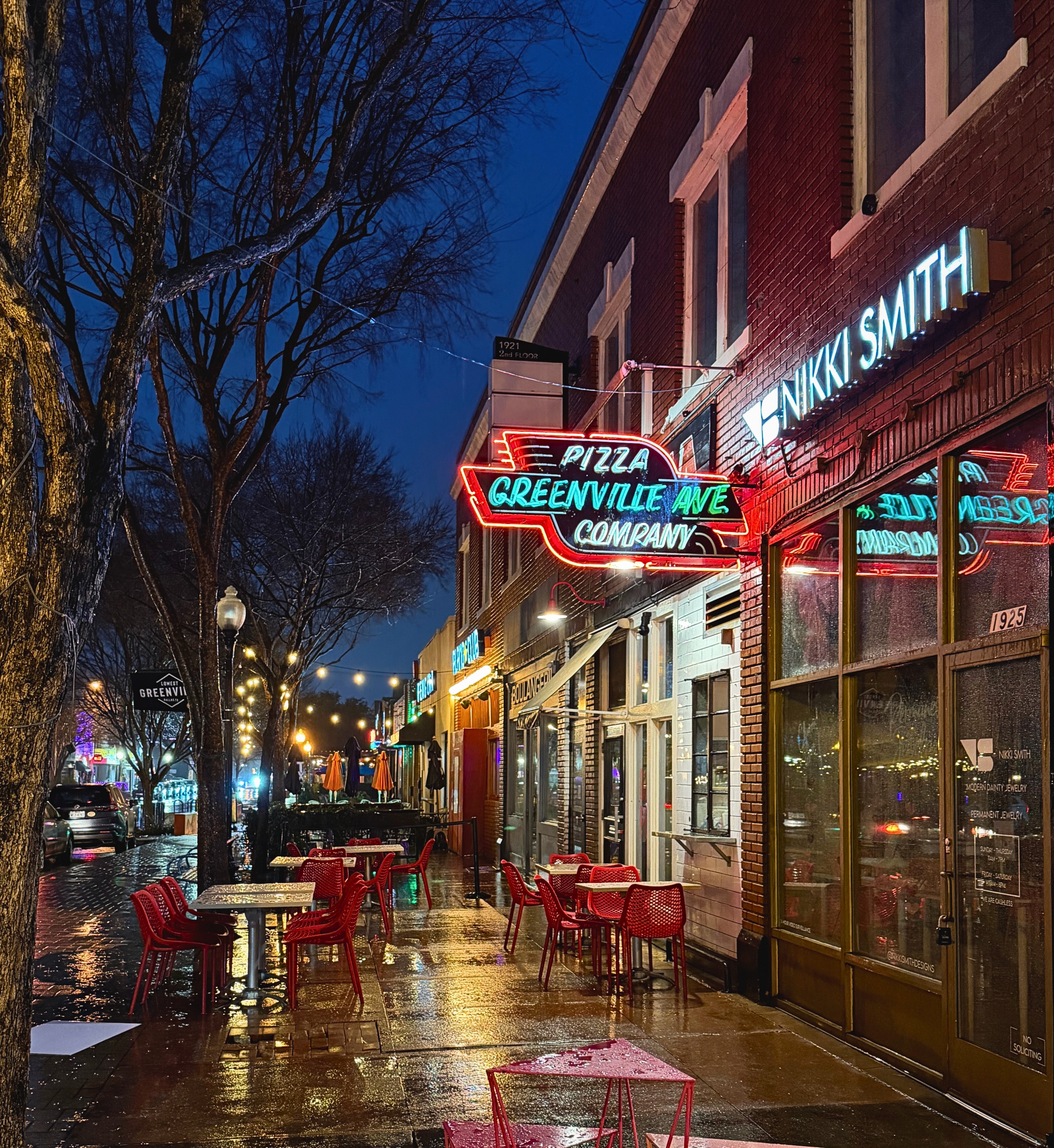 Neon signage for Greenville Avenue Pizza Company on a rainy Dallas street at night.