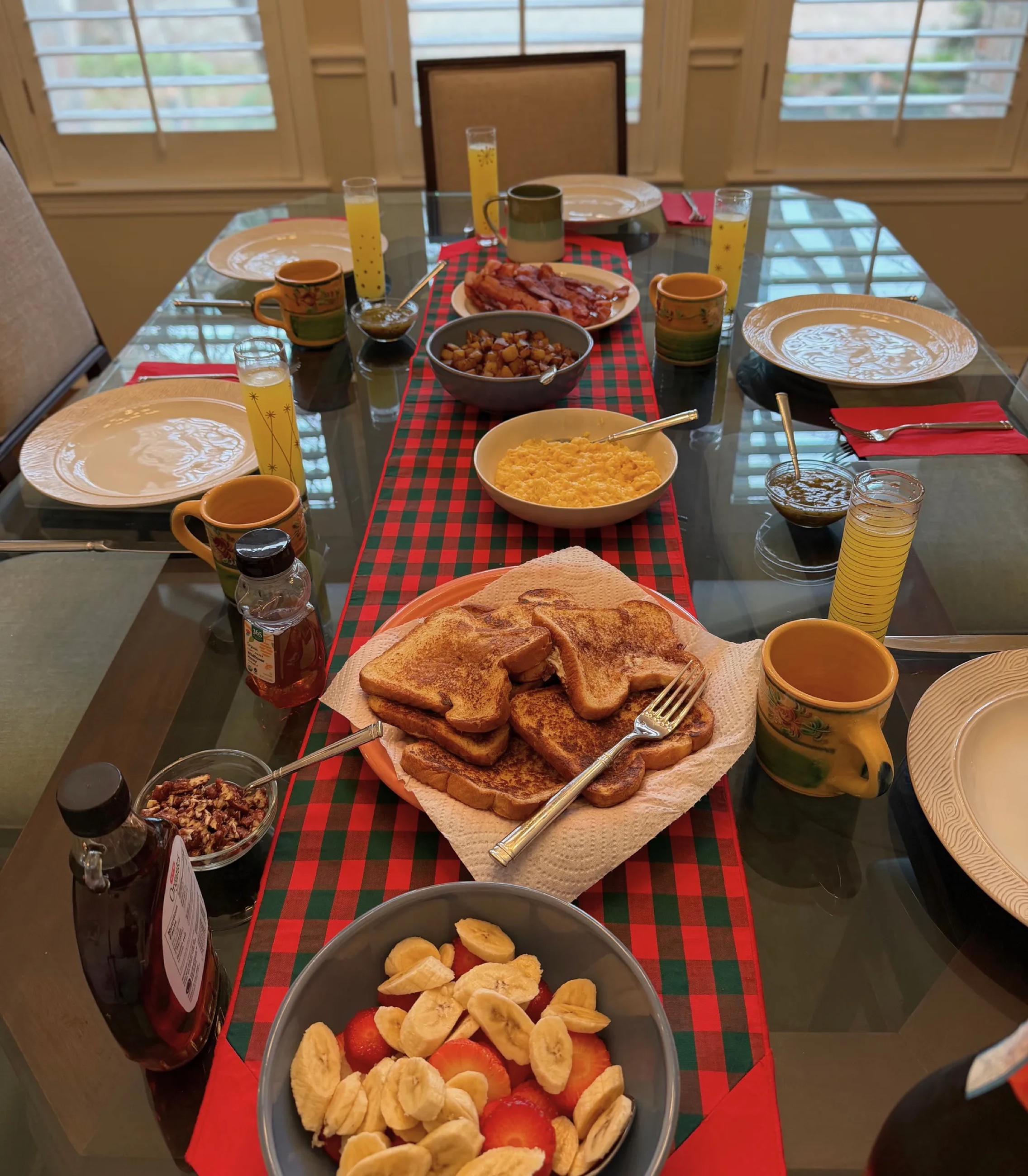 An overhead view of a New Year's Day brunch table with French toast, bacon, fruit, and mimosas.