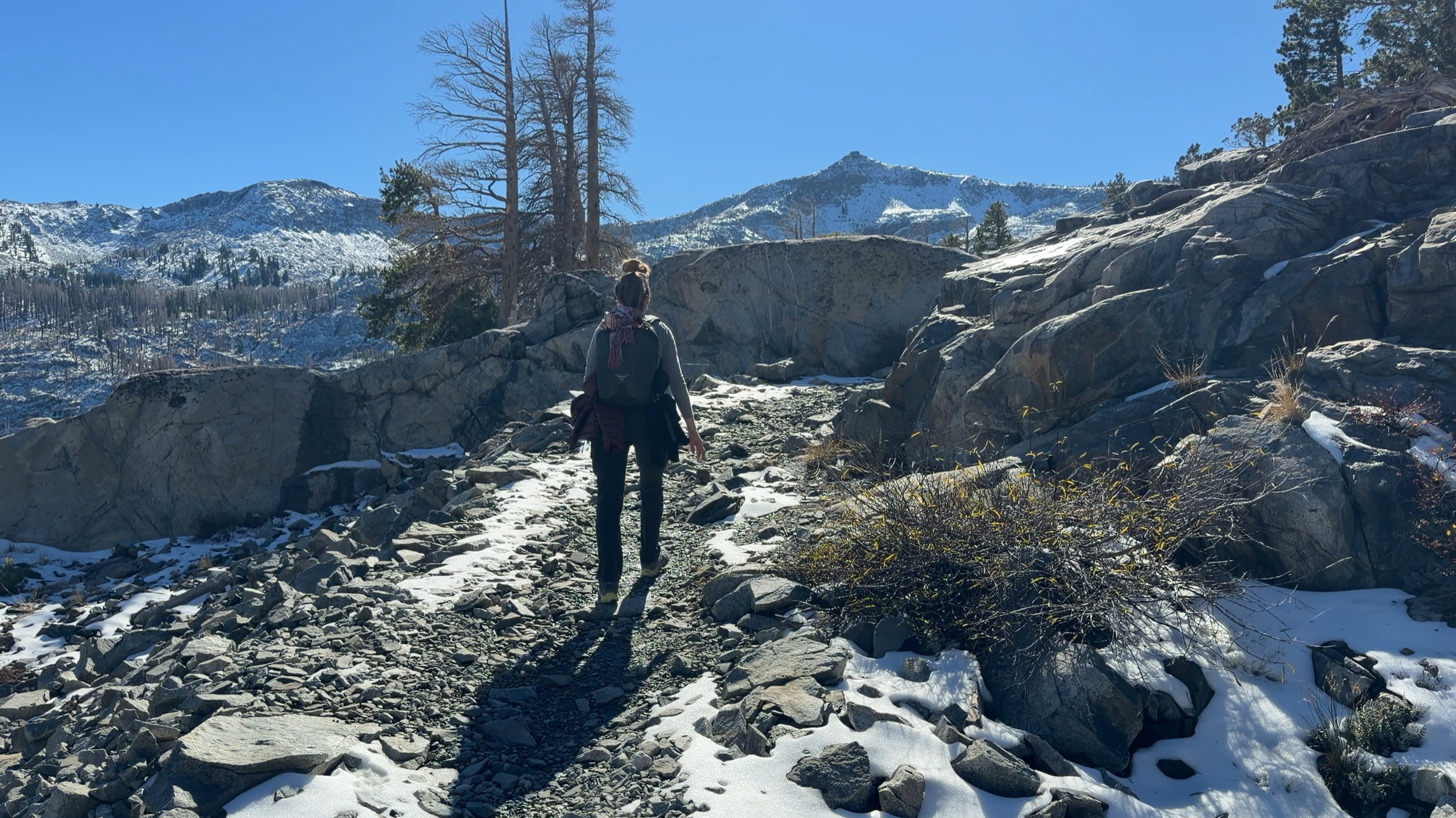 Stephanie hiking through rock and patchy snow on the approach to Tamarack Lake.