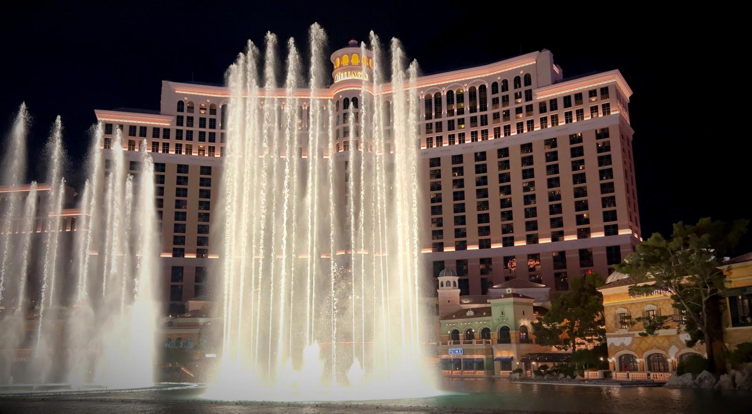 The Bellagio fountains performing at night in front of the illuminated hotel.